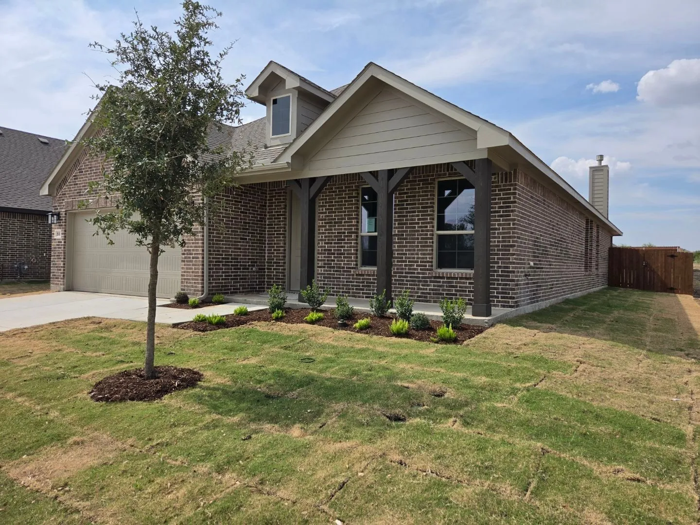 Brick exterior with a covered entry, decorative gables, and a wood privacy fence