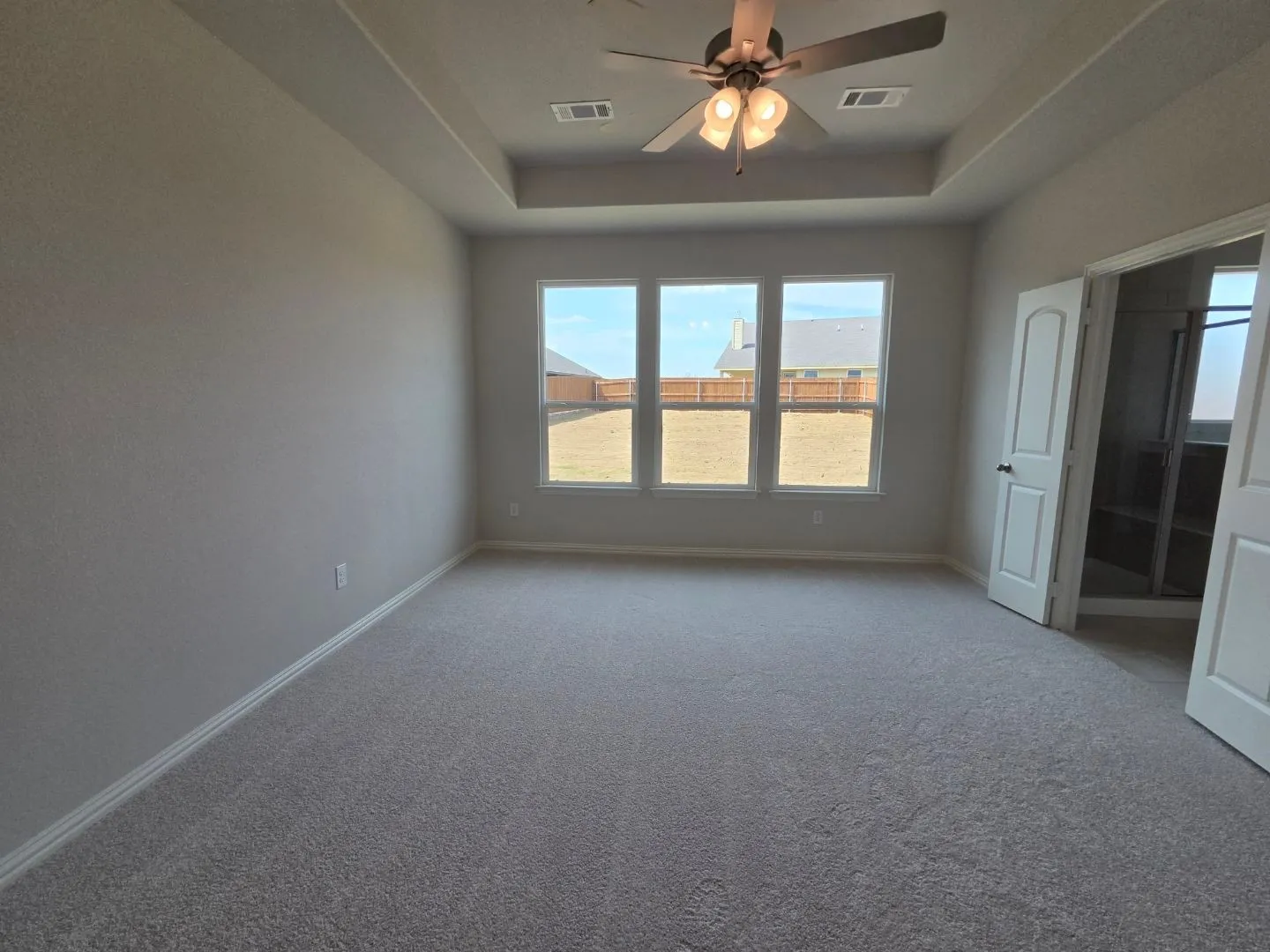 Recessed ceiling with an integrated ceiling fan and light fixture, triple-pane windows, and neutral carpeting