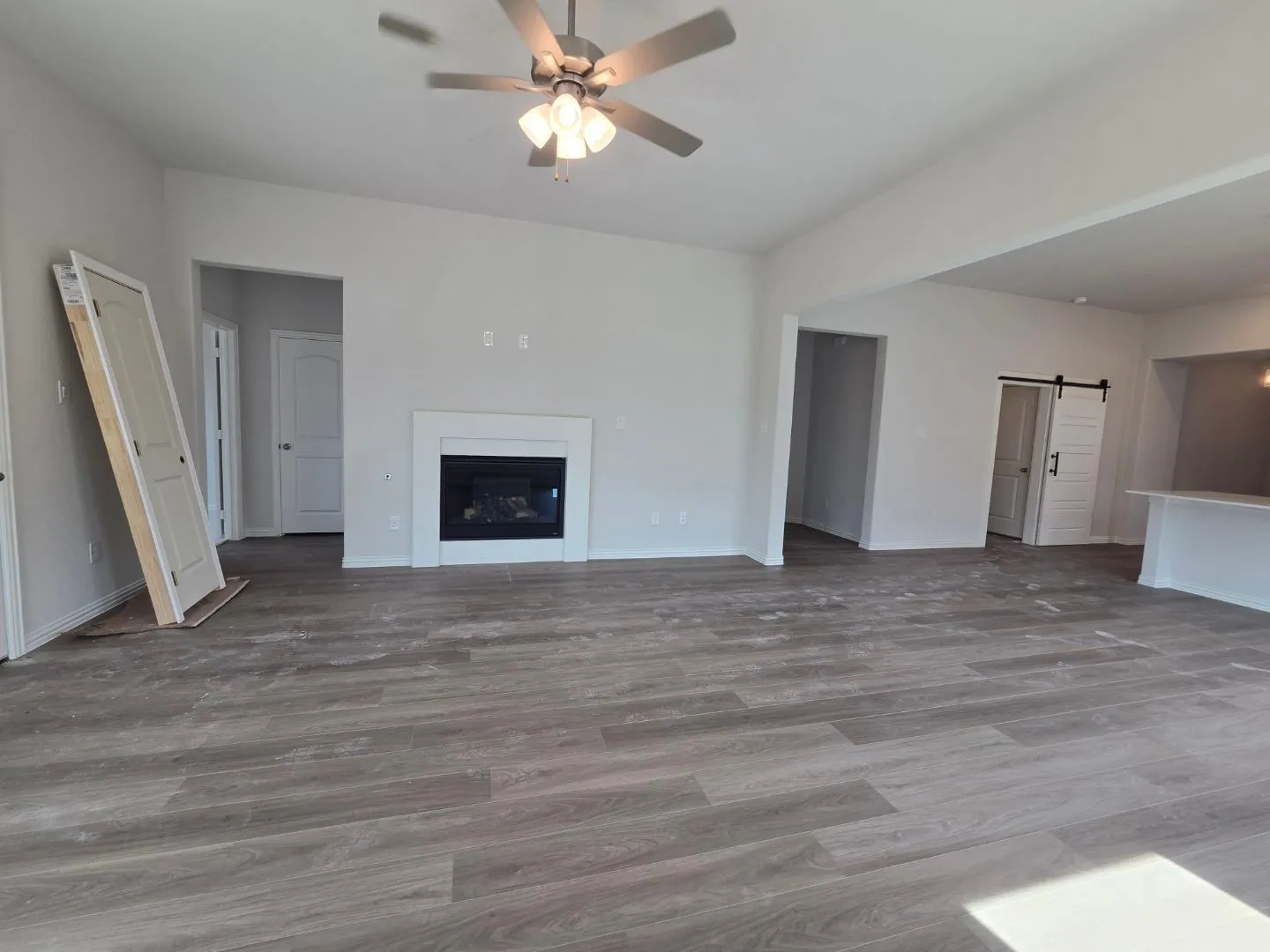 Wood-finish flooring, built-in fireplace, ceiling fan, and a barn door