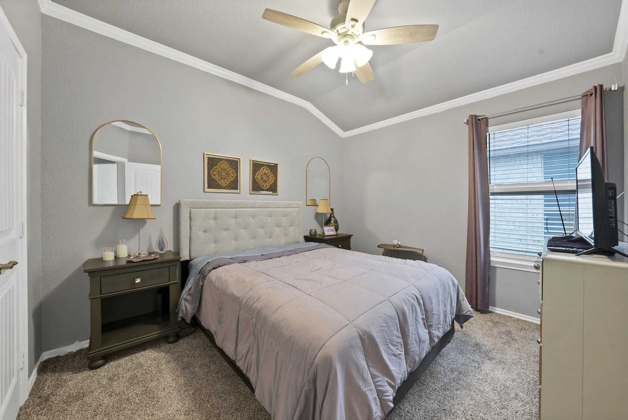 Vaulted ceiling with crown molding, ceiling fan, carpeted flooring, and a window with blinds
