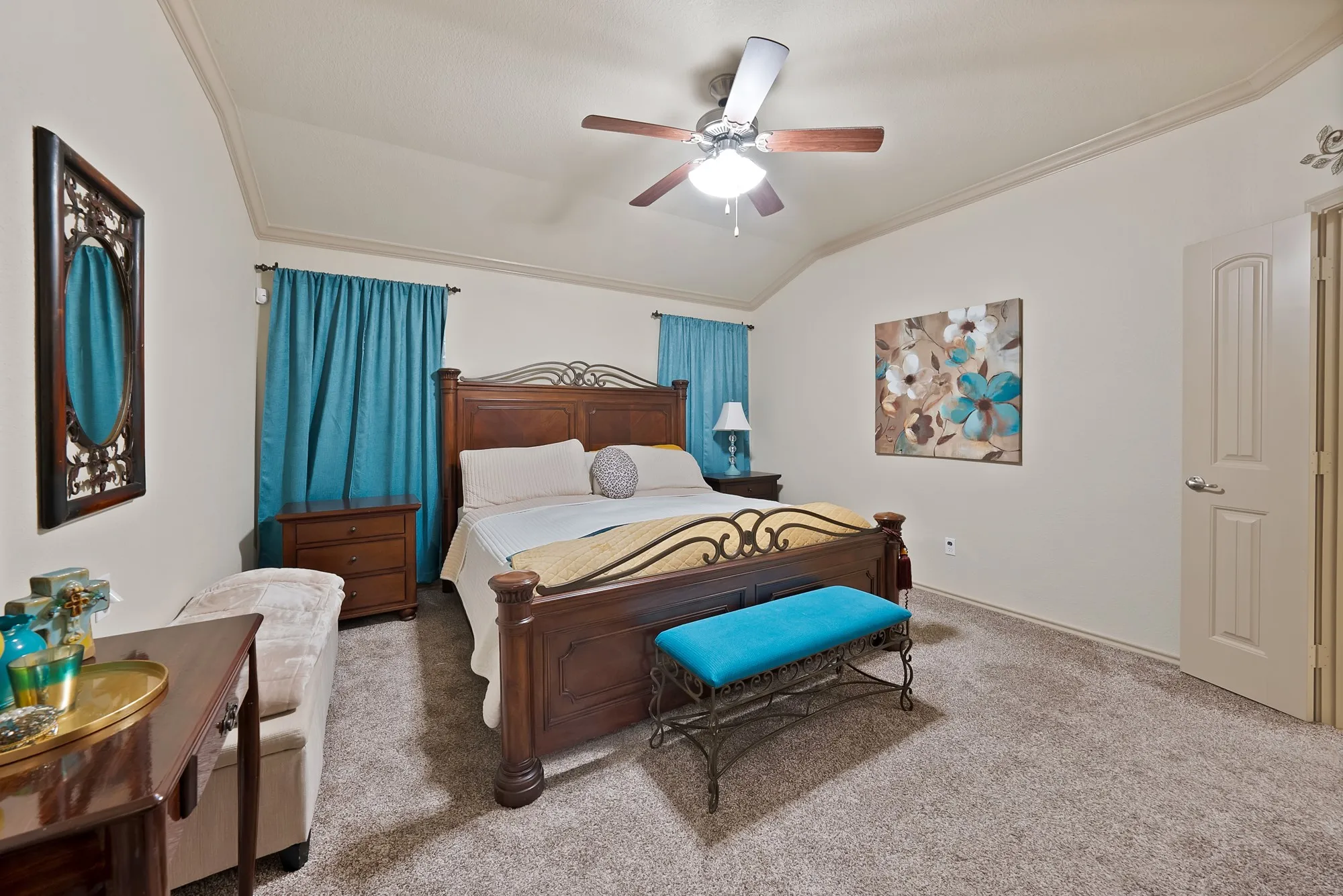 Vaulted ceiling with crown molding, ceiling fan, and light-colored carpet flooring