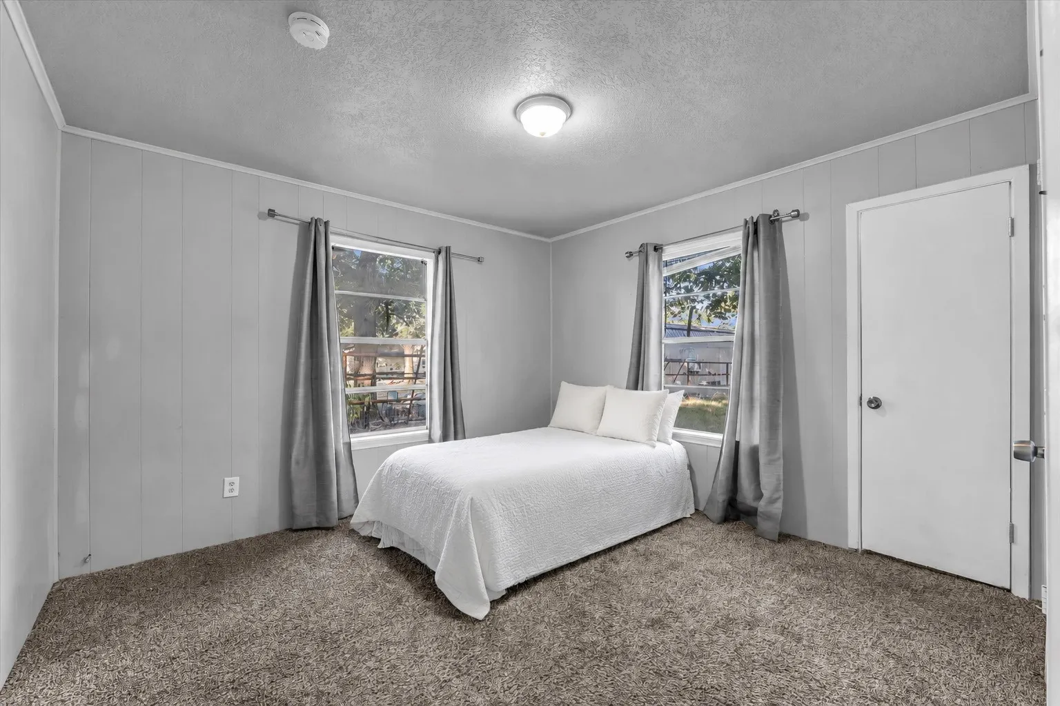 Broadloom carpeting, two windows, and paneling walls