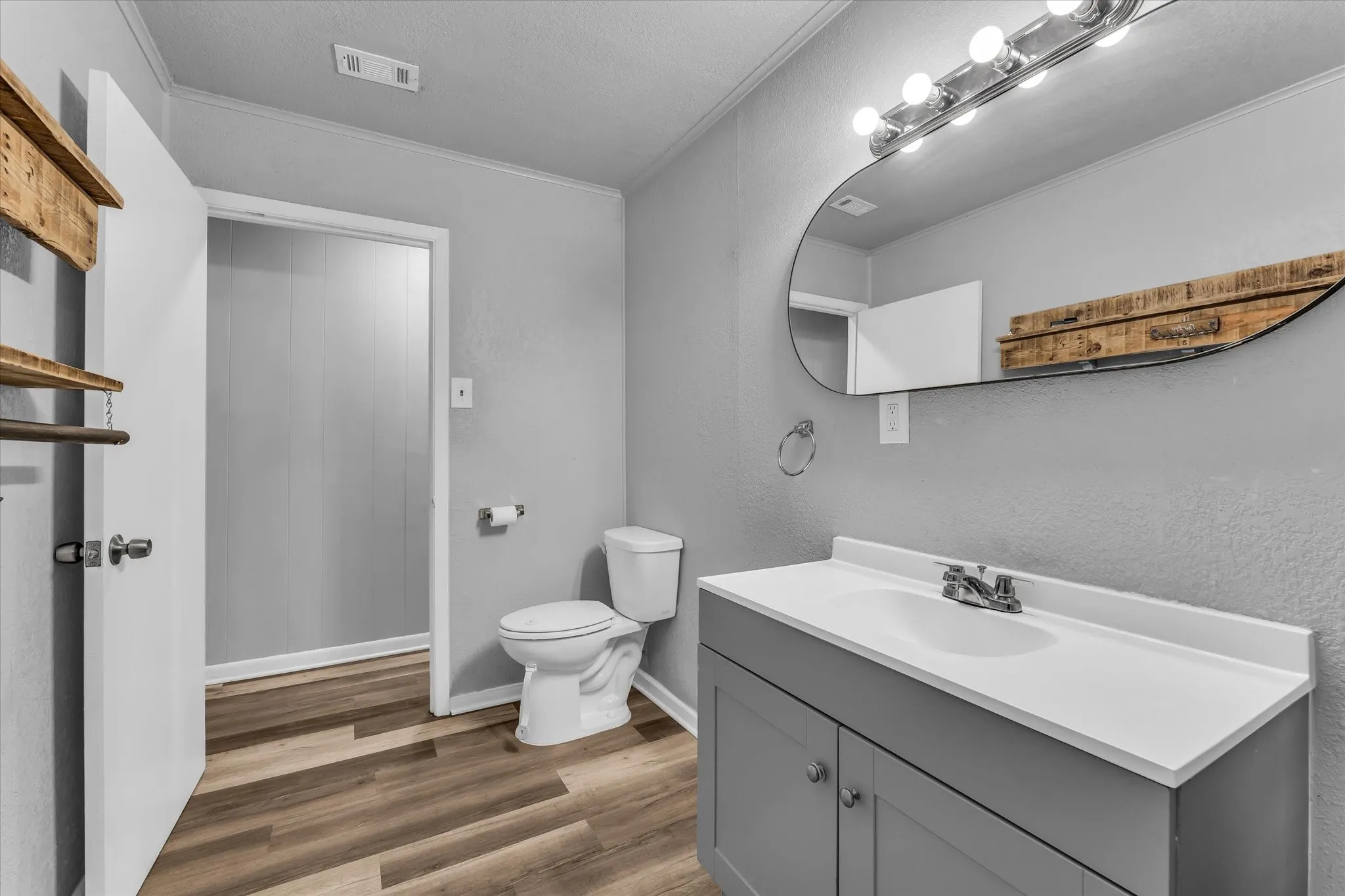Gray vanity with an integrated white sink, chrome faucet, and oval wall mirror