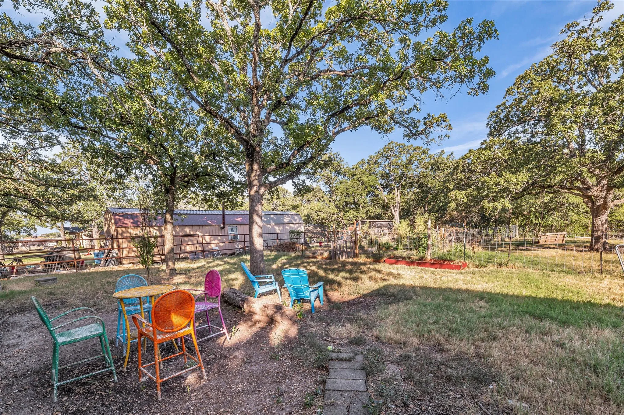 Expansive outdoor space featuring mature trees, a designated garden area, wood fencing, and a natural ground cover