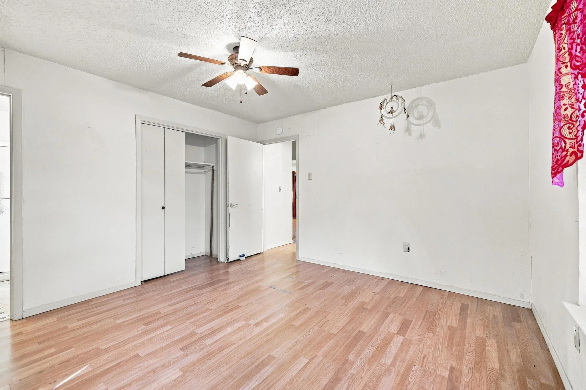 Room featuring wood-finish flooring, white walls, and a ceiling fan