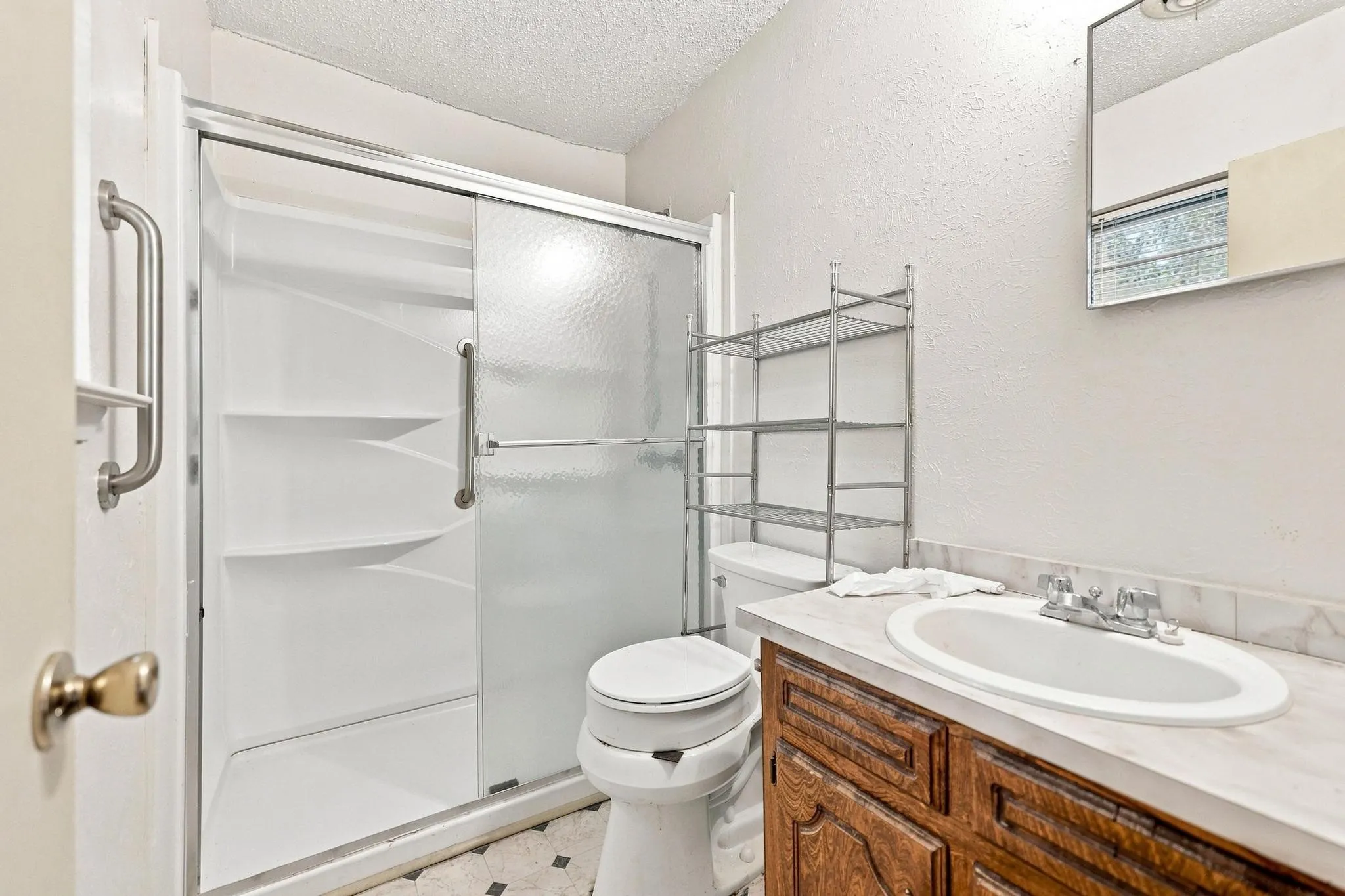 Bathroom featuring a shower with sliding glass doors, white vanity with an undermount sink, and a wall-mounted mirror
