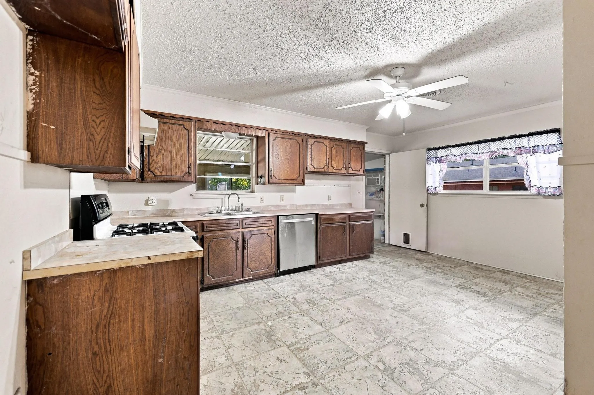Spacious kitchen featuring wood-finish cabinetry, tile flooring, and a ceiling fan