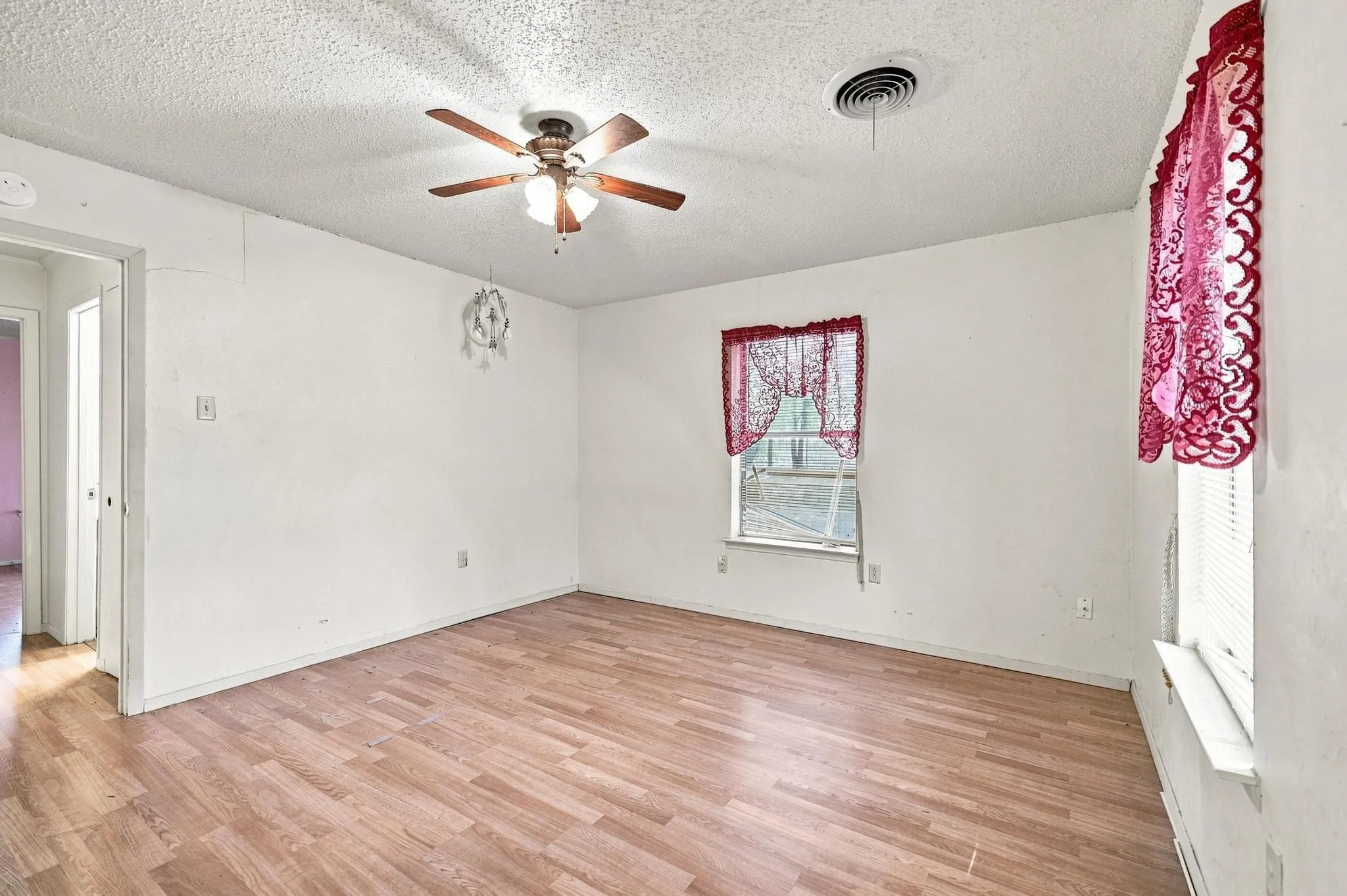 Wood-finish flooring with a ceiling fan light fixture and window