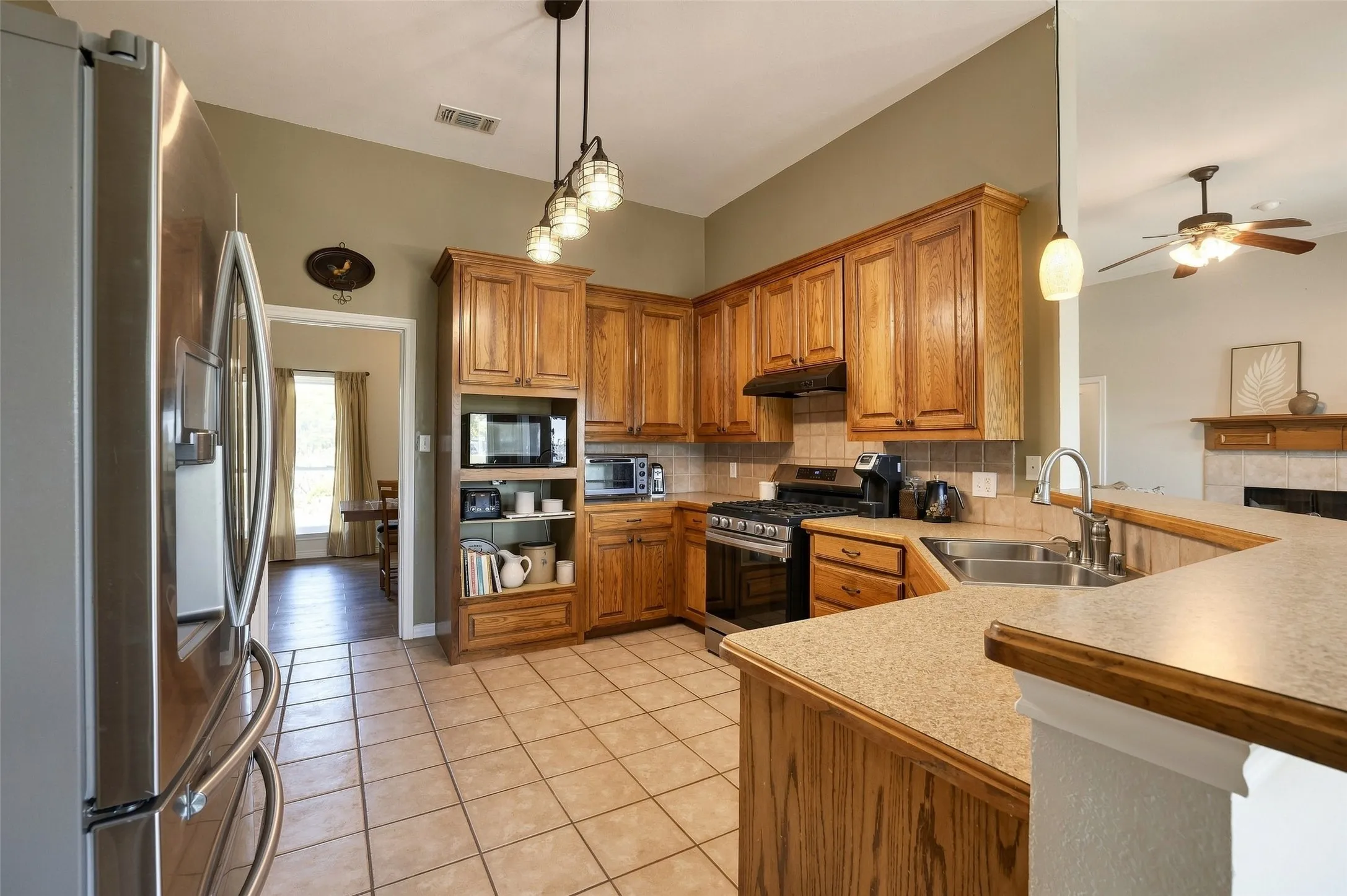 The oversize kitchen has tons of gorgeous custom wood cabinets