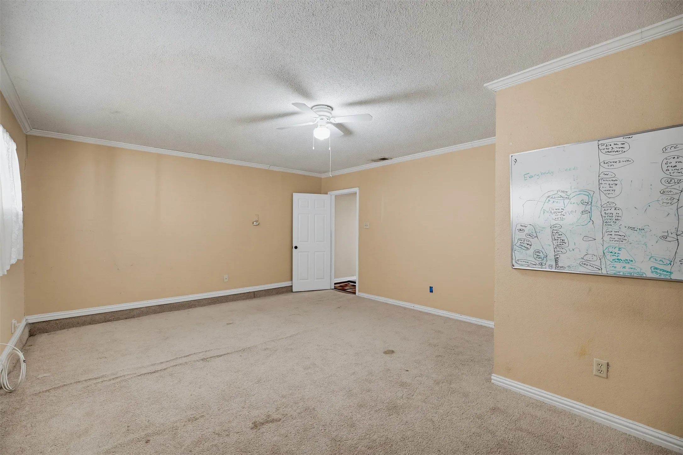 Carpeted interior space with a ceiling fan, crown molding, and a paneled interior door