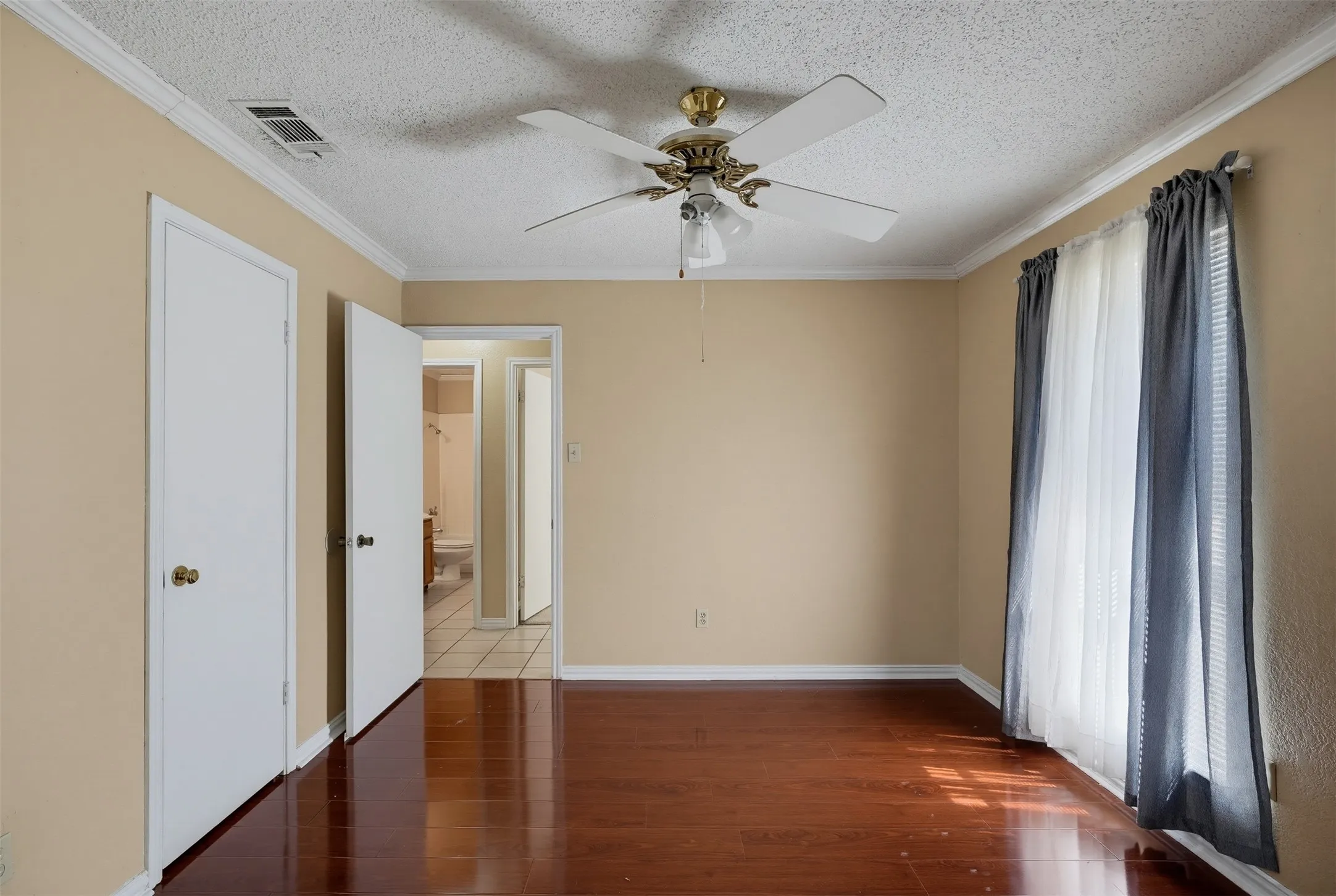 Wood-finish flooring, crown molding, and a ceiling fan