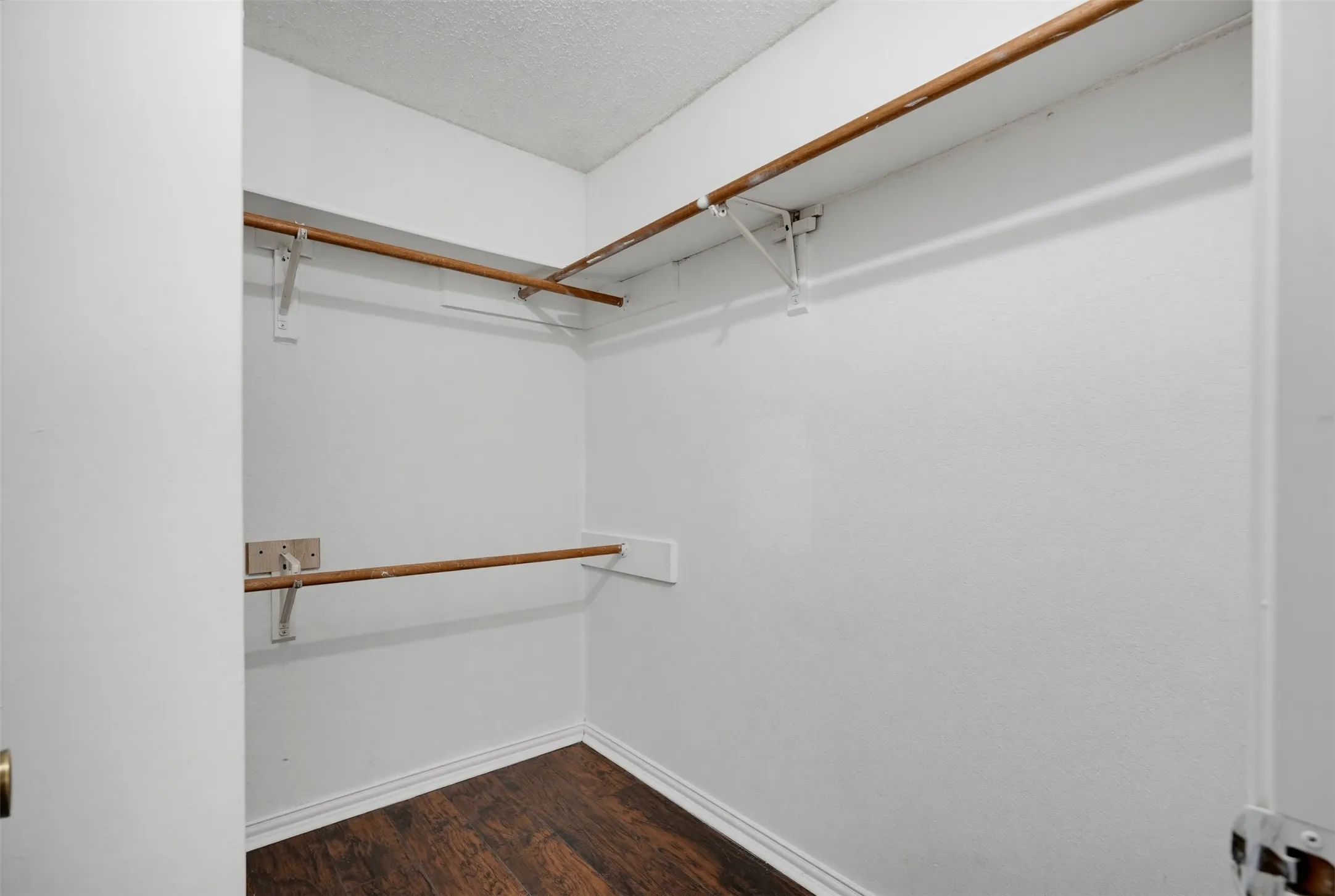 Wood-finish flooring with white baseboards and painted white walls