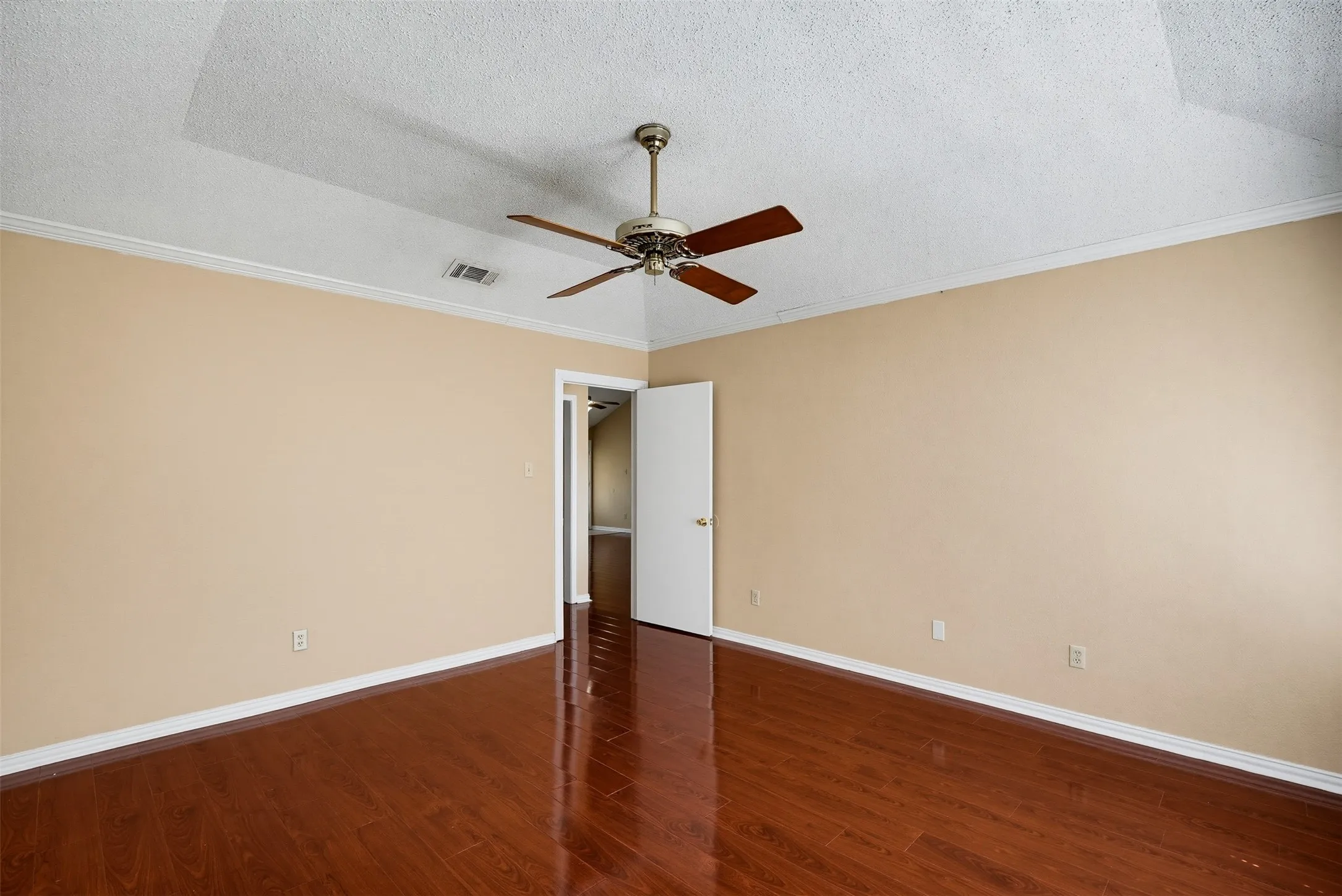 Wood-finish flooring, ceiling fan, crown molding, and a vaulted ceiling