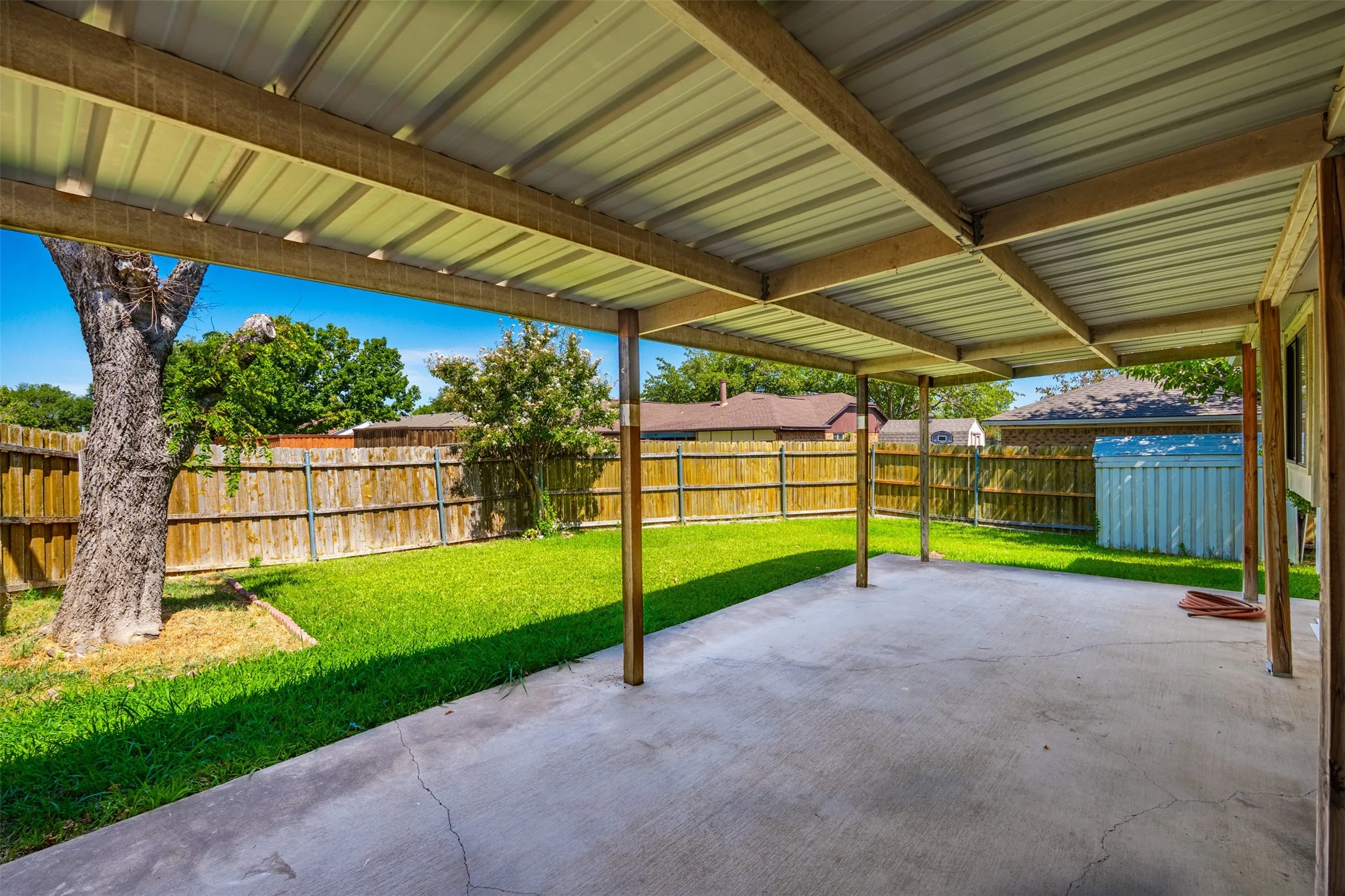 Covered concrete patio with metal roof and wood support beams