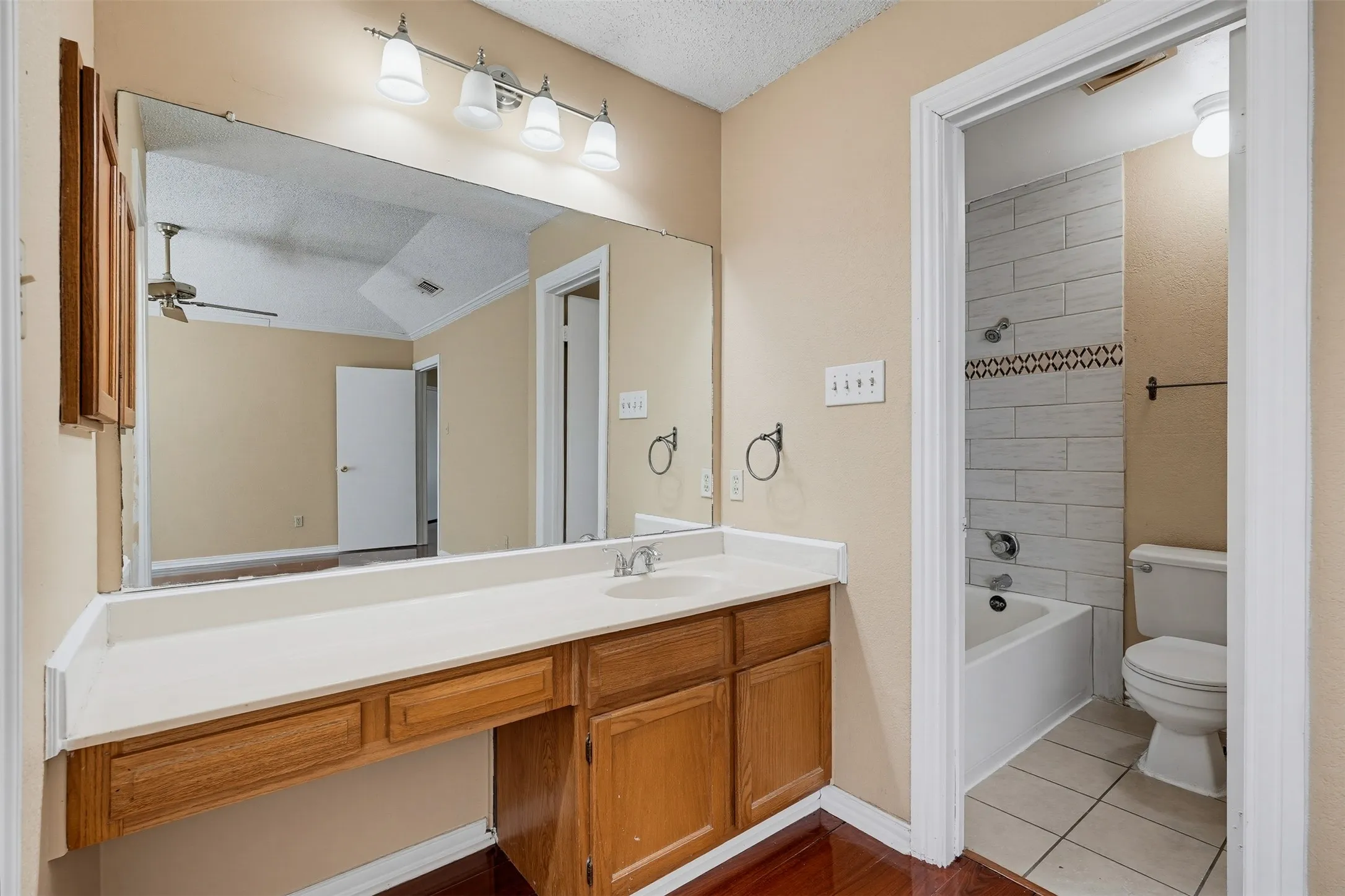 Vanity with integrated sink, wood-finish cabinetry, and a full-width mirror