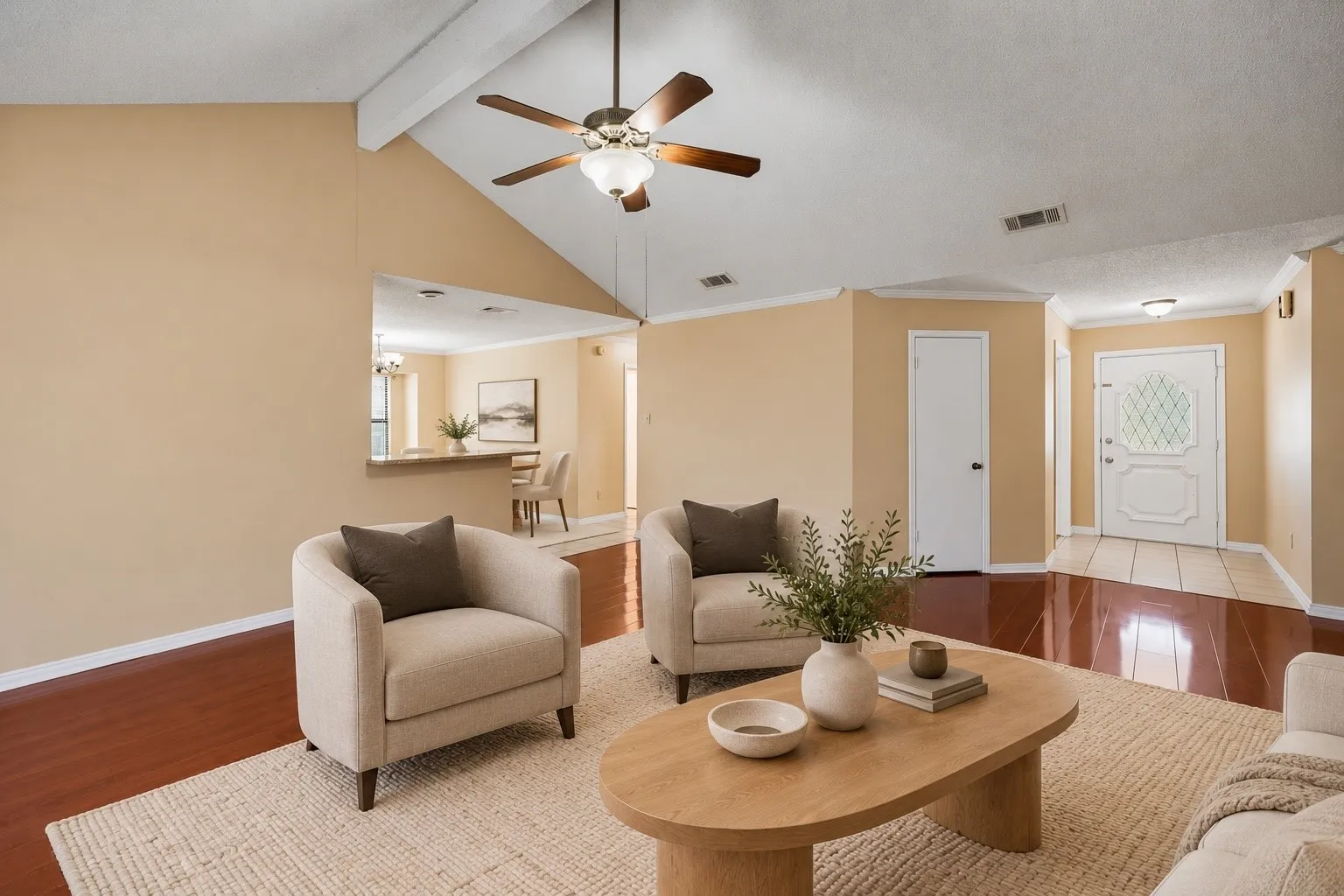 Vaulted ceilings with exposed beams, wood-finish flooring, ceiling fan with integrated lighting, and a front entry door with decorative glass inserts