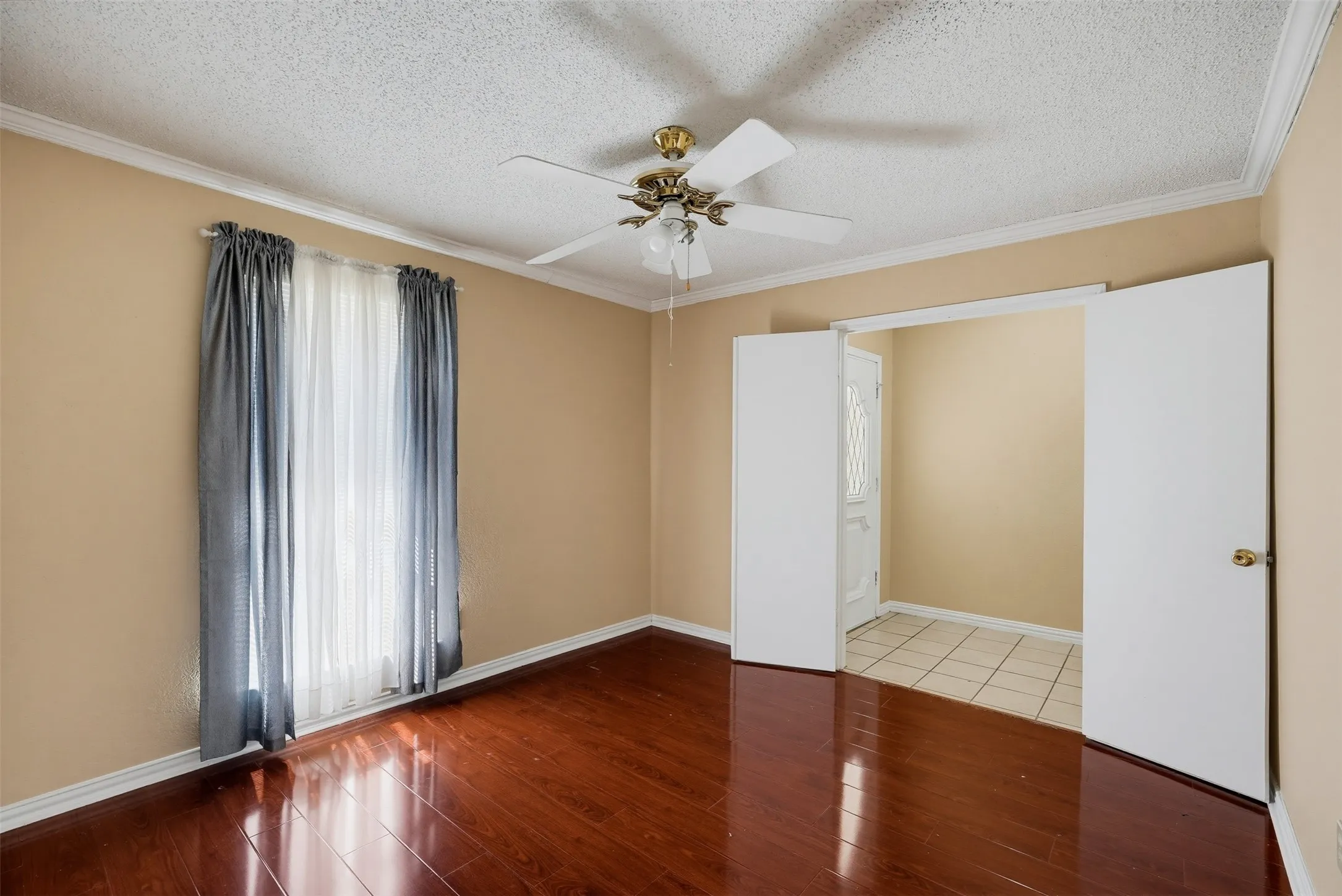 Polished wood-finish flooring, ceiling fan with light fixture, crown molding, and double entry doors