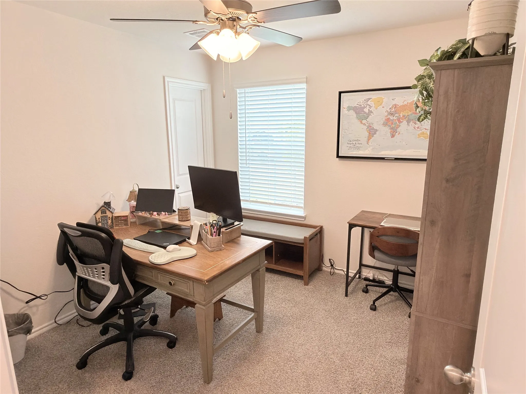 Carpeted room with a ceiling fan light fixture, window with blinds, and white door