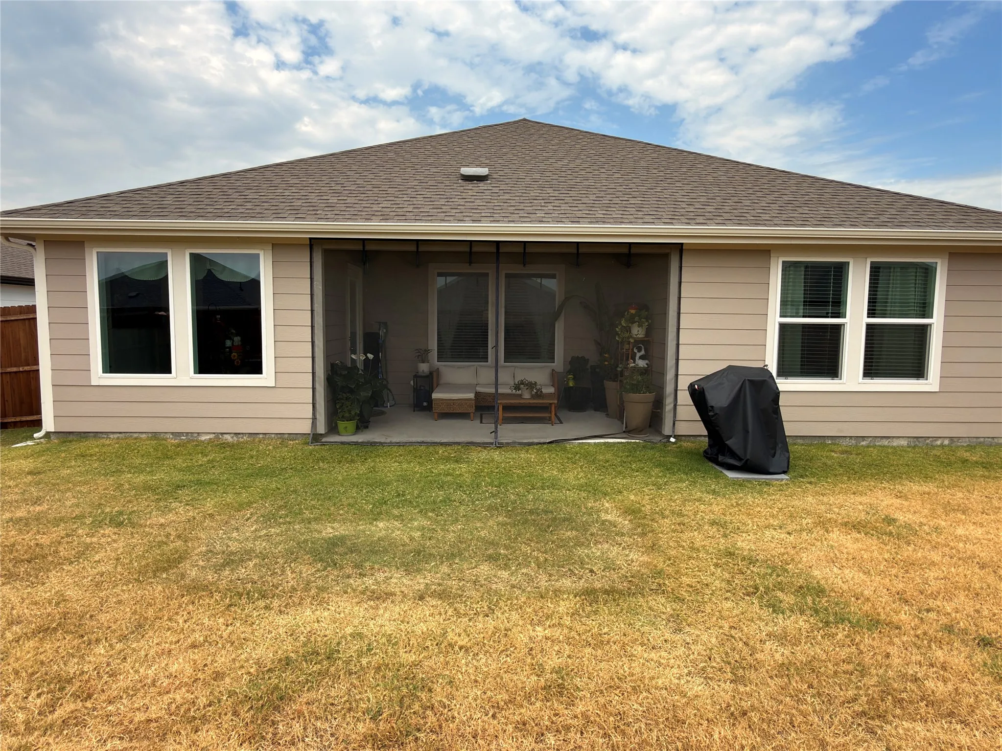 Rear elevation featuring a screened-in patio, neutral-toned siding, white window trim, and a shingled roof