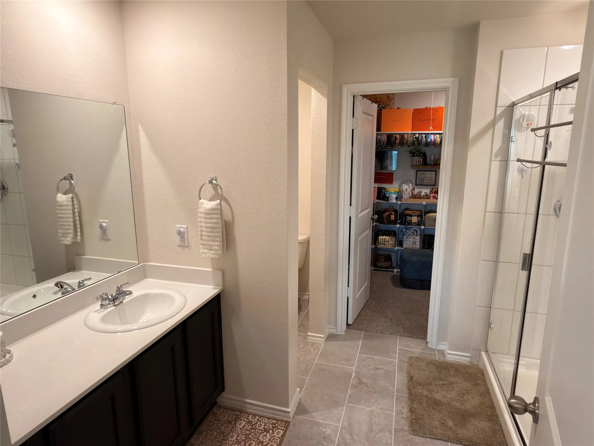 Bathroom featuring a single vanity with a white countertop, an undermount sink, and a framed mirror