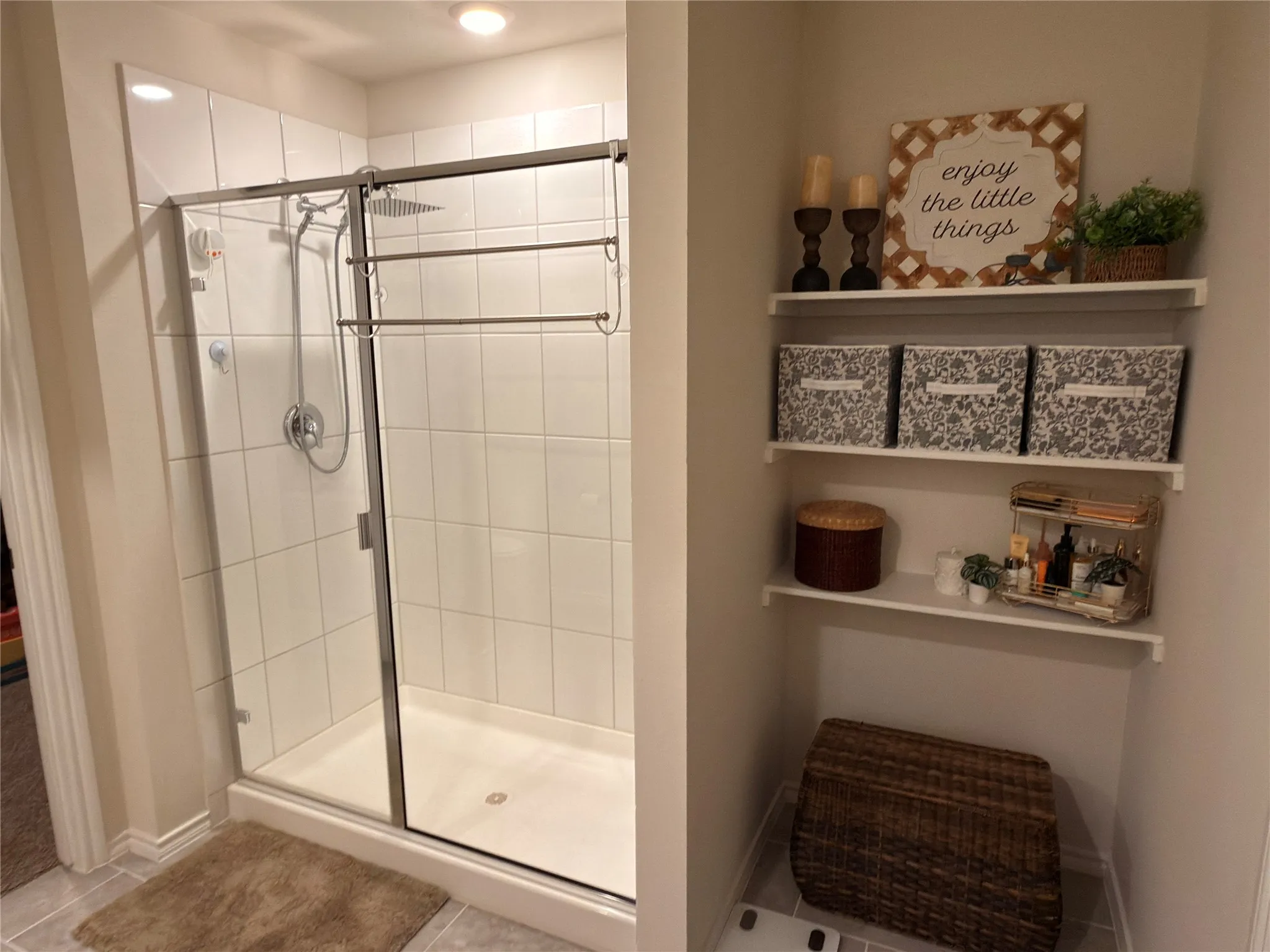 Glass-enclosed shower with white tiled walls and a built-in shelf system