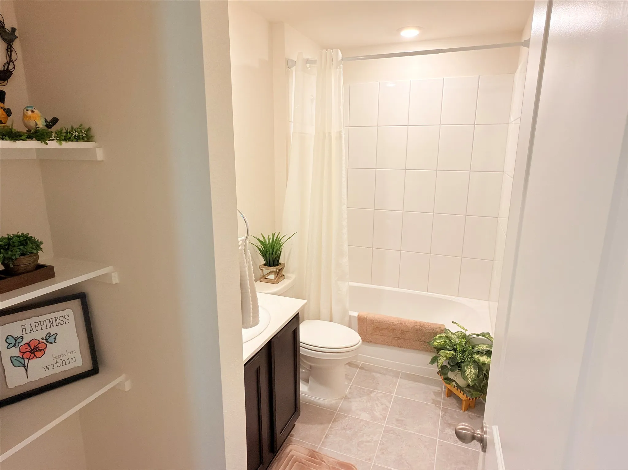 Bathroom featuring a built-in bathtub with white tile surround, white vanity with a countertop, dark wood-finish cabinetry, and light-colored floor tiles