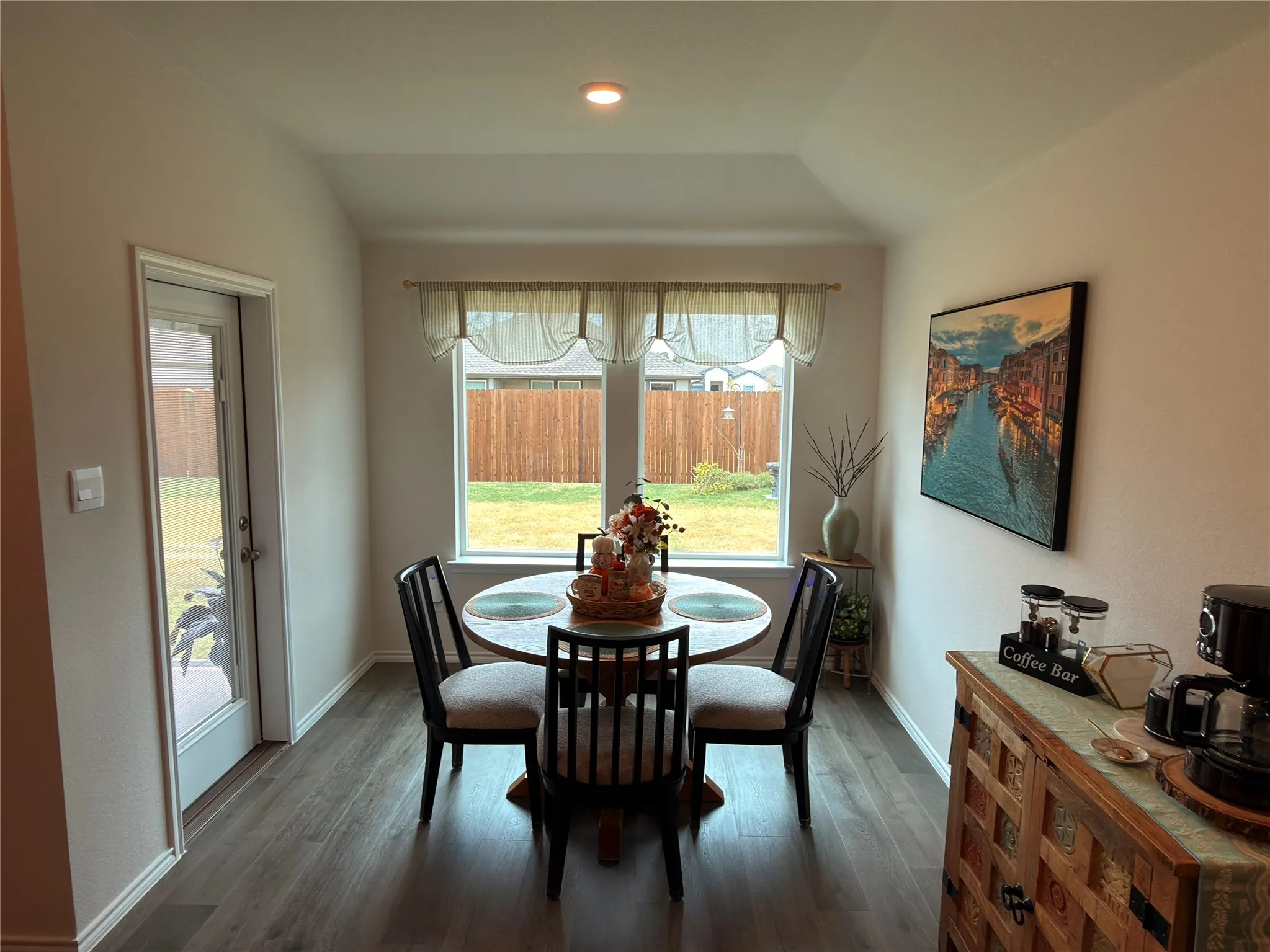 Tray ceiling, recessed lighting, wood-finish flooring, two windows with backyard views, and a glass-paneled exterior door