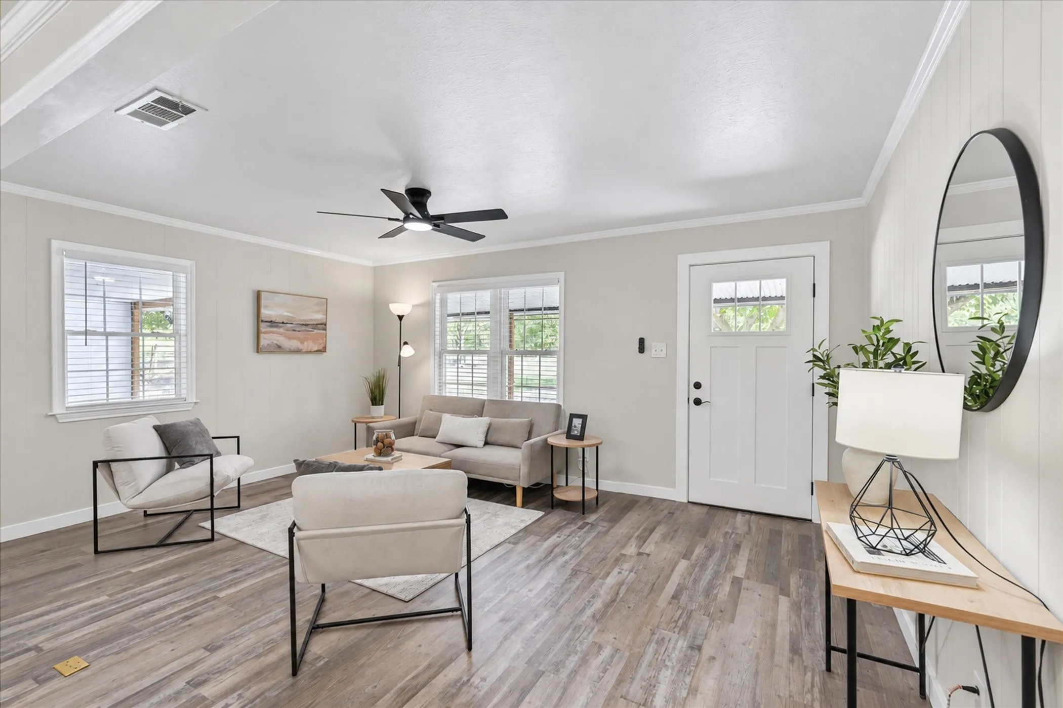 Open-concept living space featuring wood-finish flooring, a modern ceiling fan, and crown molding