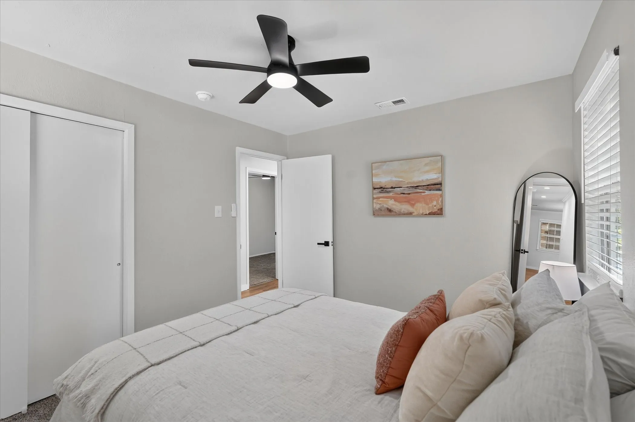 Ceiling fan with integrated lighting, window with horizontal blinds, neutral wall paint, white interior doors, and sliding closet doors