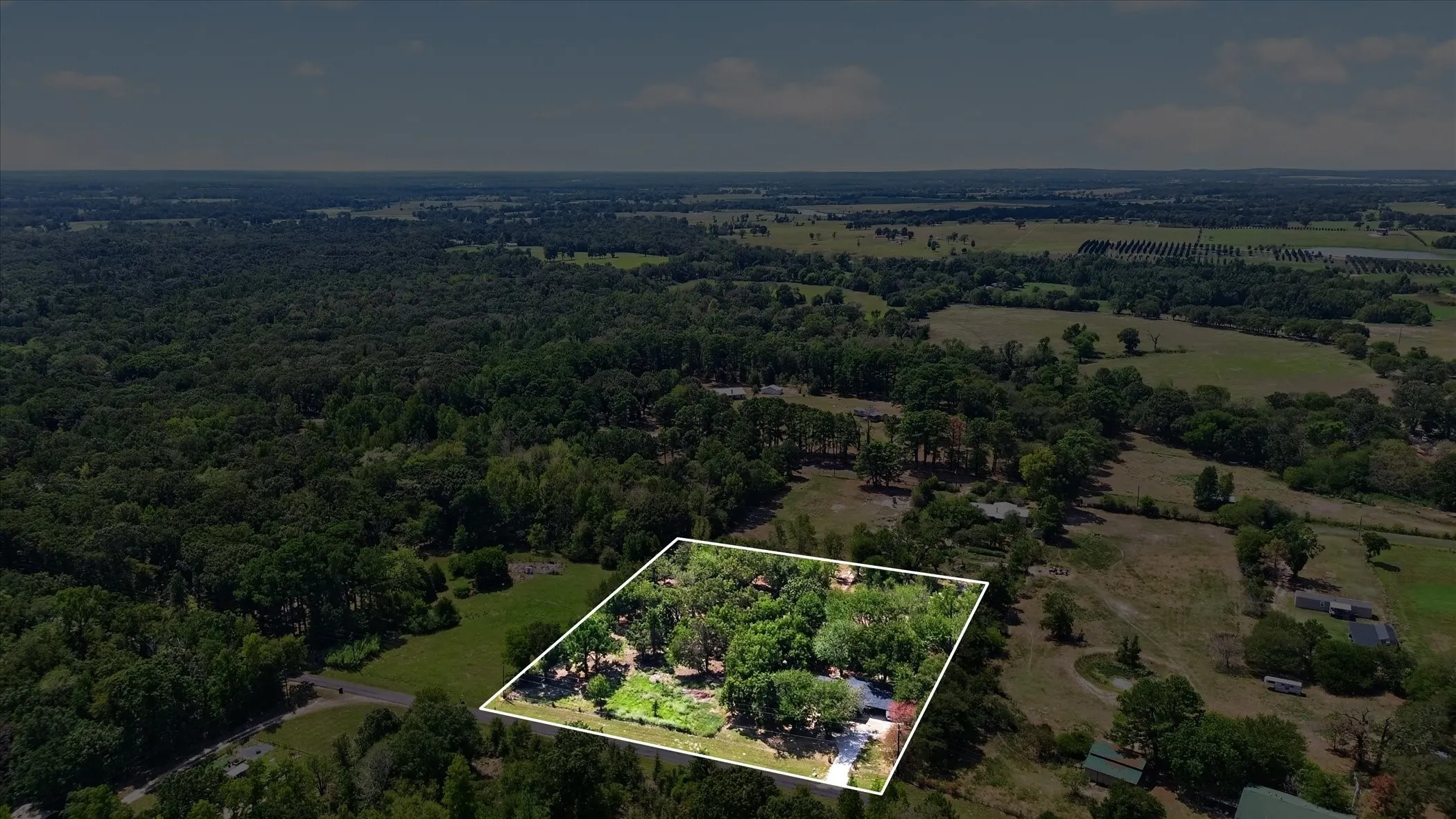 Rural property with a tree-lined perimeter and expansive surrounding natural landscape