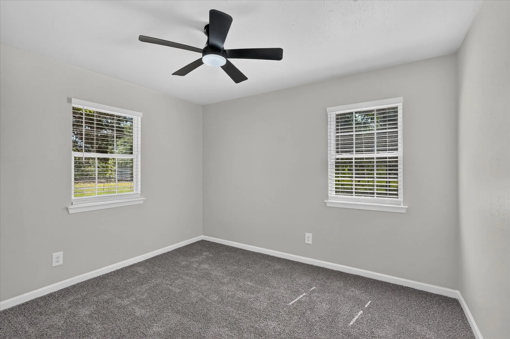 Recessed lighting with a ceiling fan, dual windows with blinds, light gray wall paint, and gray carpet flooring