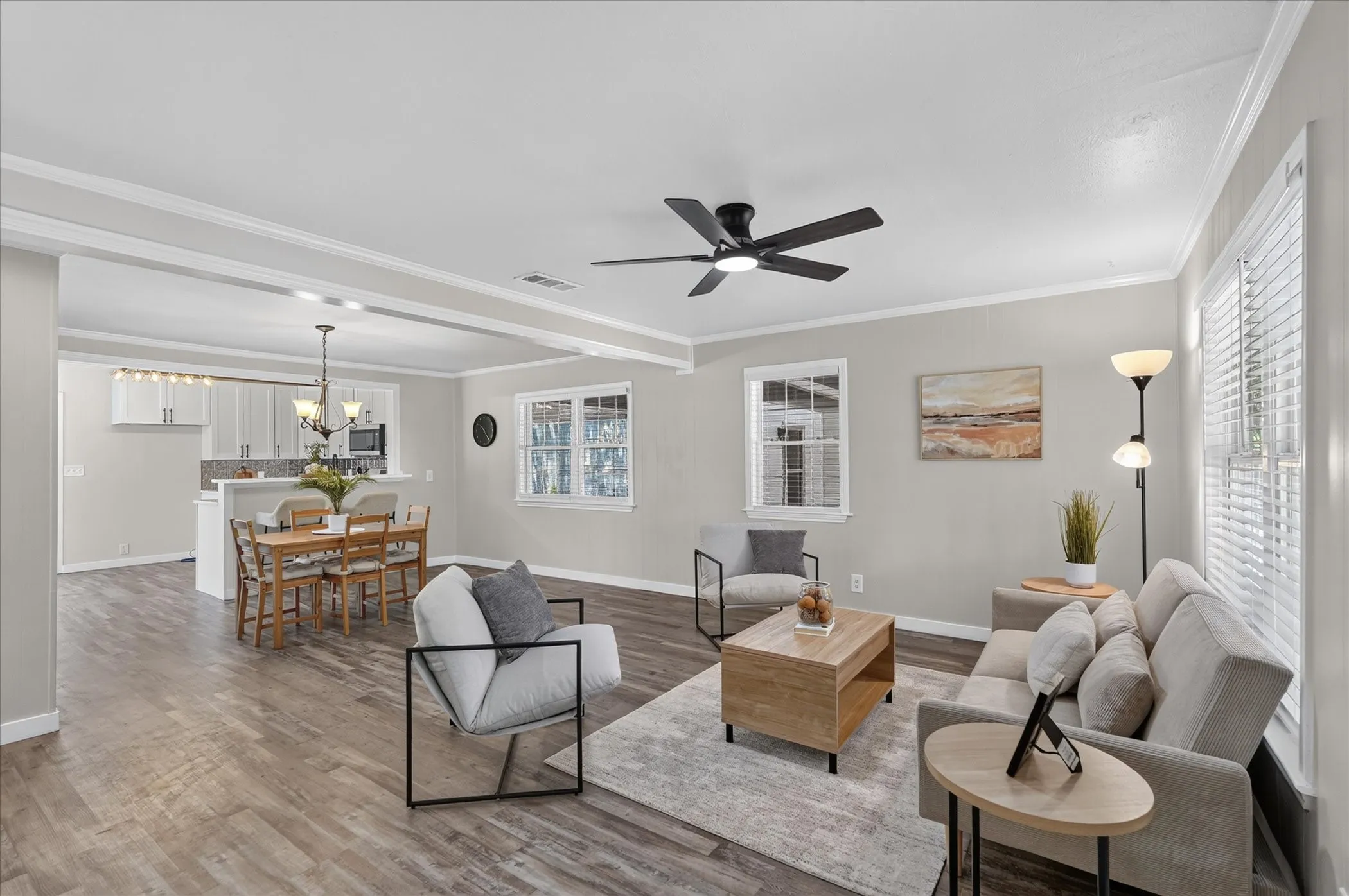 Spacious living area featuring wood-finish flooring, recessed lighting, ceiling fan, and crown molding