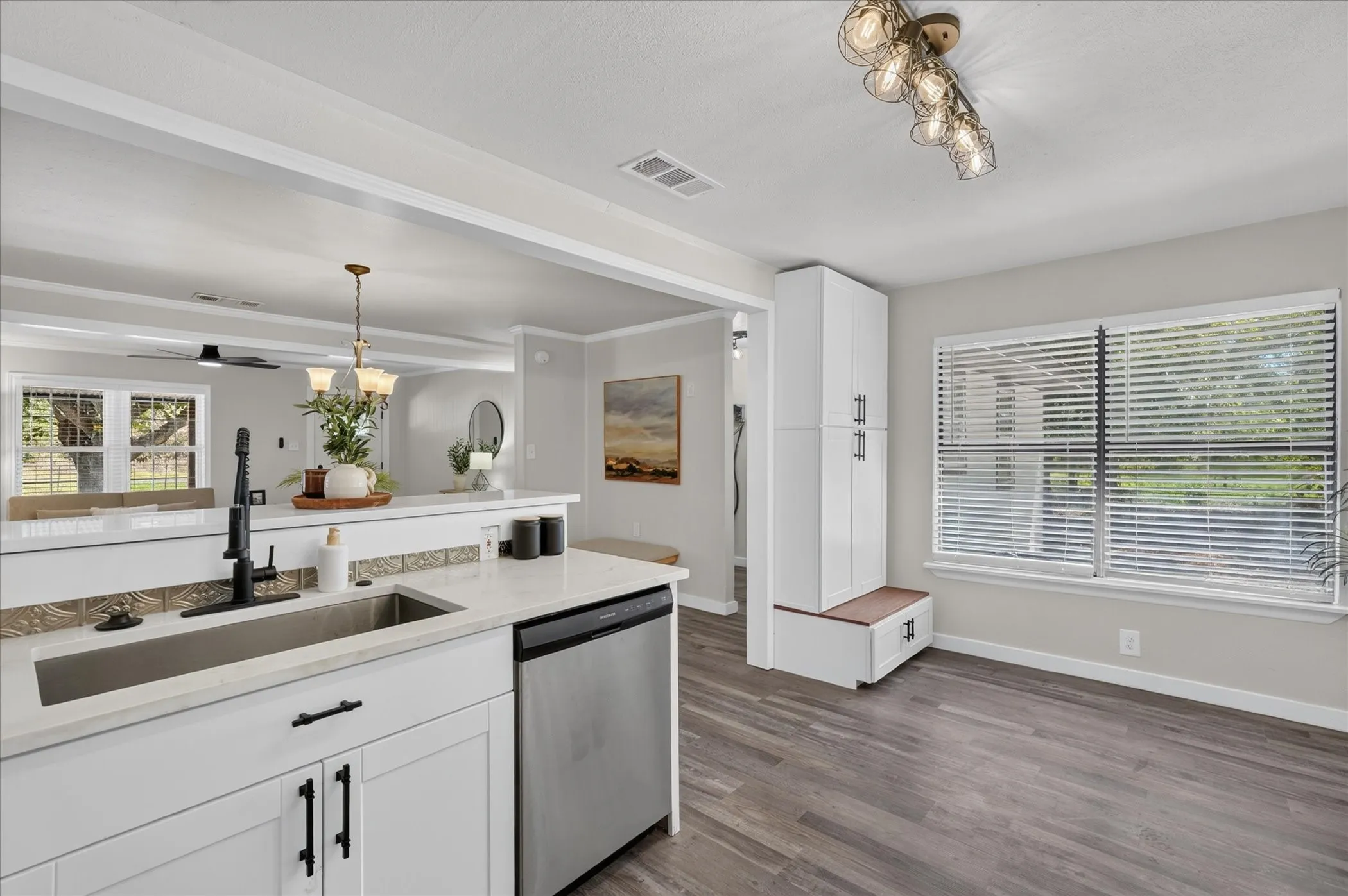 Integrated kitchen and dining area featuring wood-finish flooring, white cabinetry, and stainless steel appliances