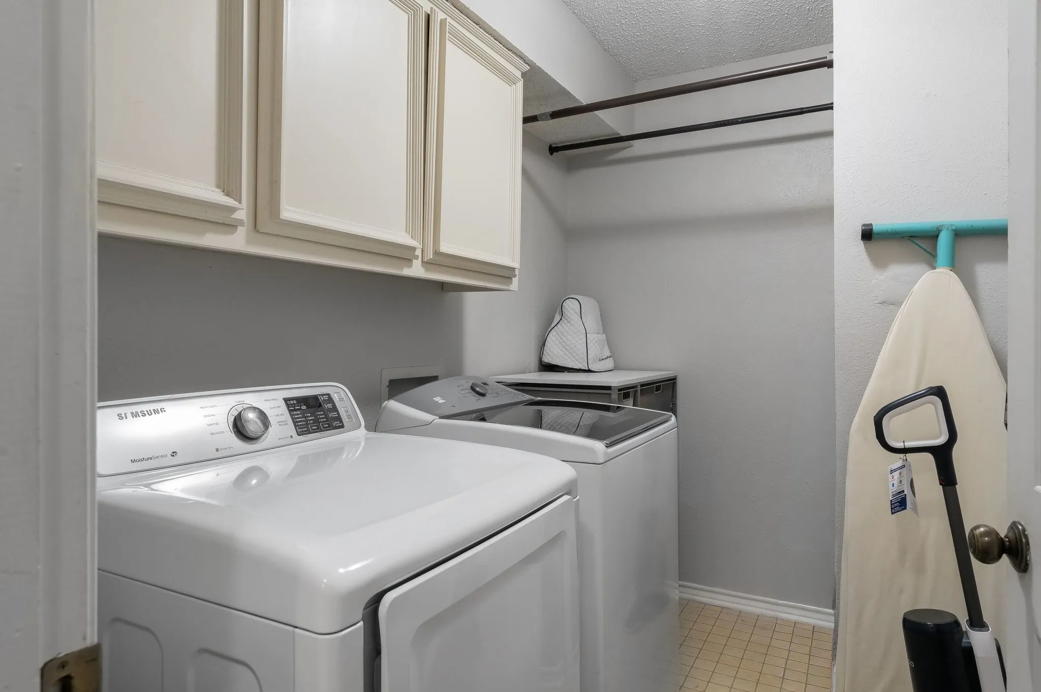 Built-in overhead cabinetry, two clothing rods, and tile flooring
