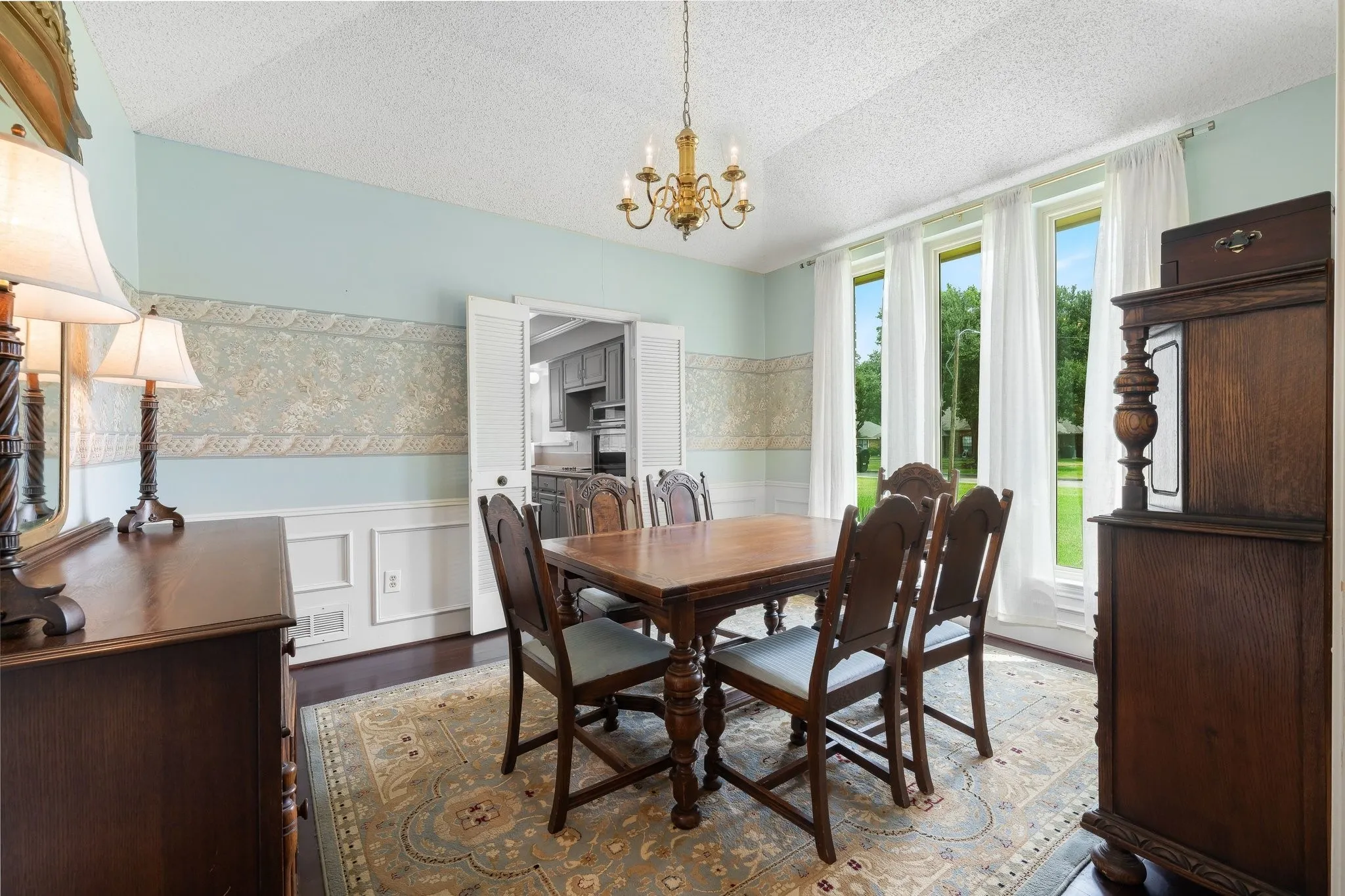 Dining room featuring wood-finish flooring, wainscoting, and a brass chandelier