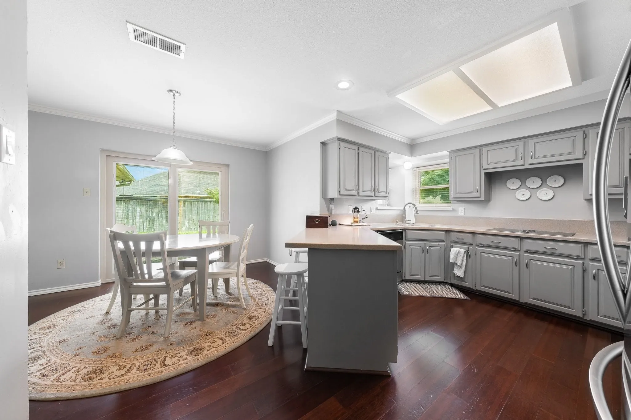Kitchen featuring wood-finish flooring, gray cabinetry, light countertops, and a built-in kitchen island