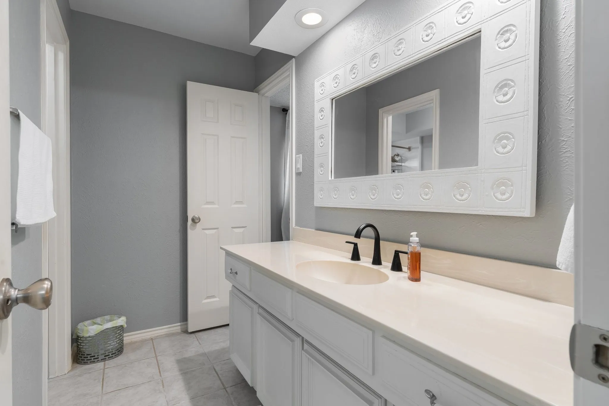 Jack and Jill bathroom.  Vanity with a light-toned countertop, undermount sink, and matte black faucet