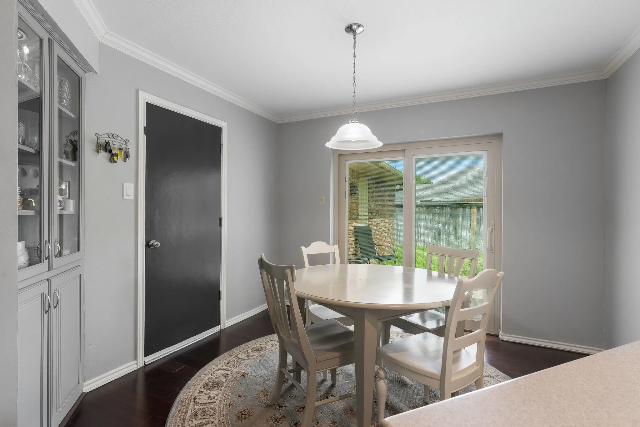 Built-in cabinetry with glass panel doors, dark wood-finish flooring, sliding glass door, crown molding, and a dome pendant light fixture