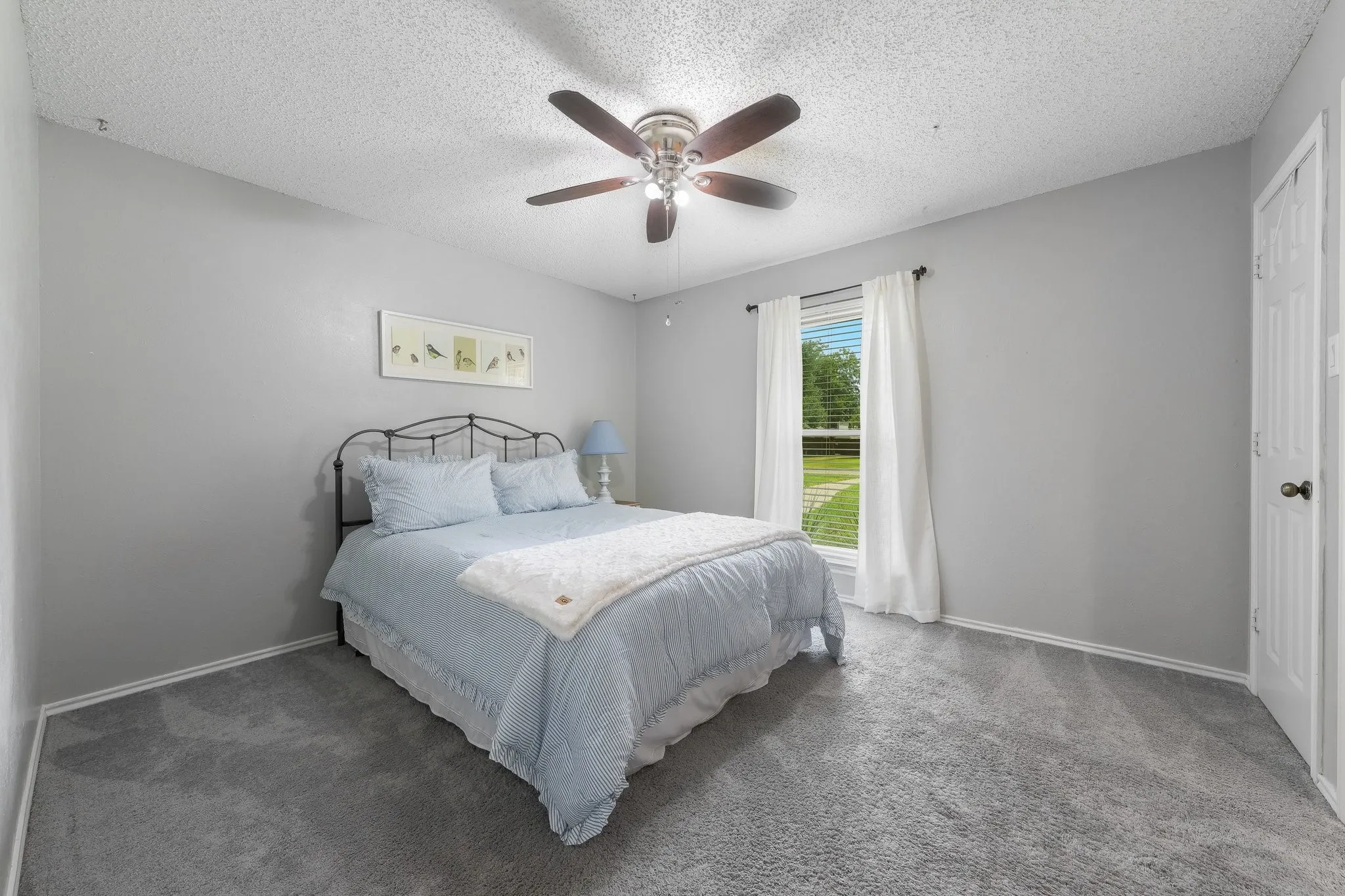 Neutral gray walls, textured white ceiling, carpeted flooring, ceiling fan, and white trim molding