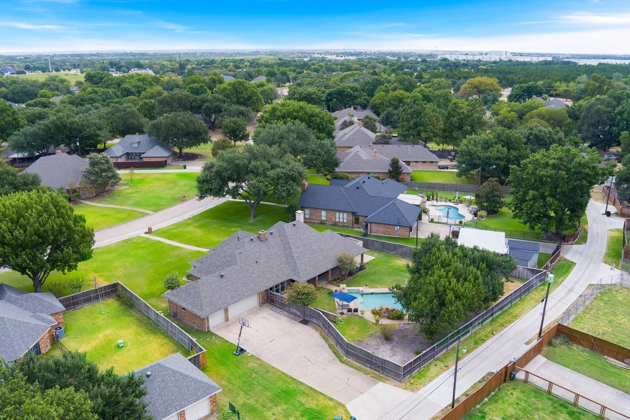 Spacious residential property with a multi-car driveway, a private swimming pool, and mature trees, set within a developed neighborhood