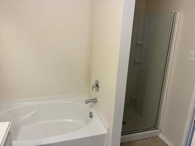 Built-in soaking tub with chrome fixtures and an adjacent glass-enclosed shower