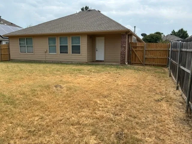 Fenced backyard with wood siding exterior and a shingle roof