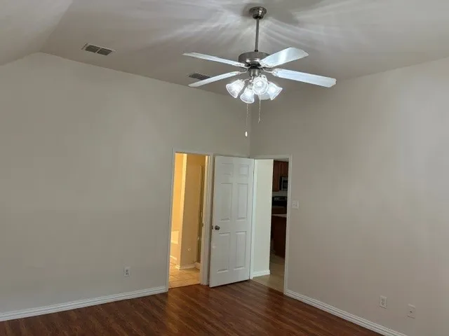 Vaulted ceiling with a brushed nickel ceiling fan, wood-finish flooring, and white trim