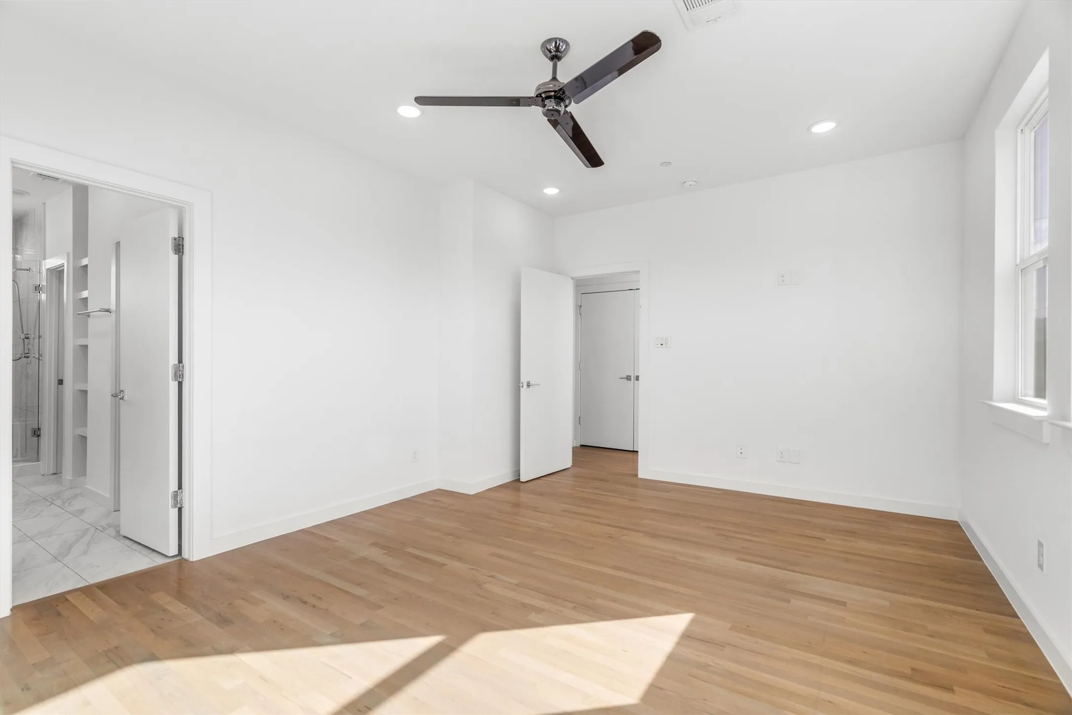 Hardwood flooring, recessed lighting, ceiling fan, white paneled doors, and a double-hung window