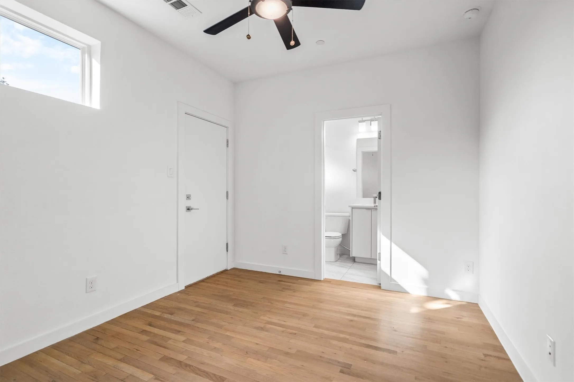 Hardwood flooring, high ceilings, ceiling fan, transom window, and a white interior