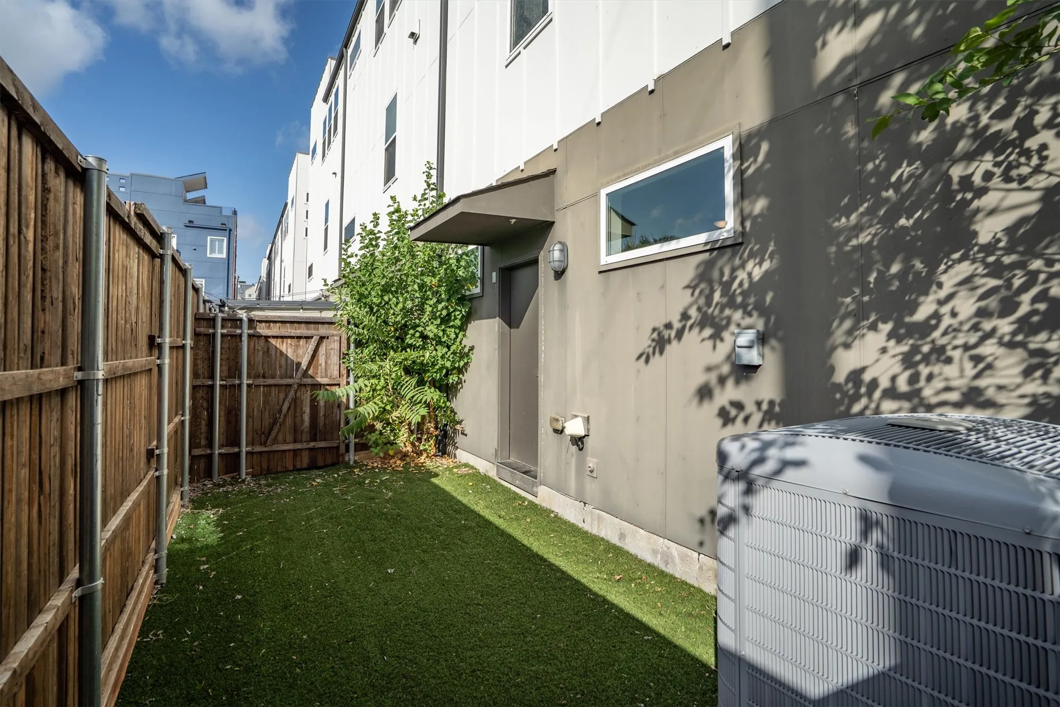 Private outdoor area with artificial turf, wood fencing, and a side gate
