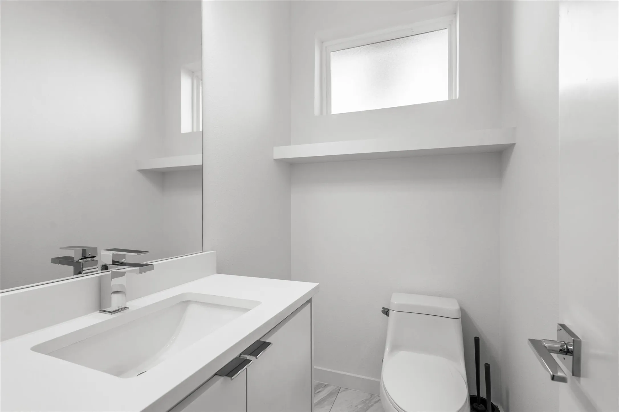 White vanity with an integrated rectangular sink, chrome faucet, and white countertop