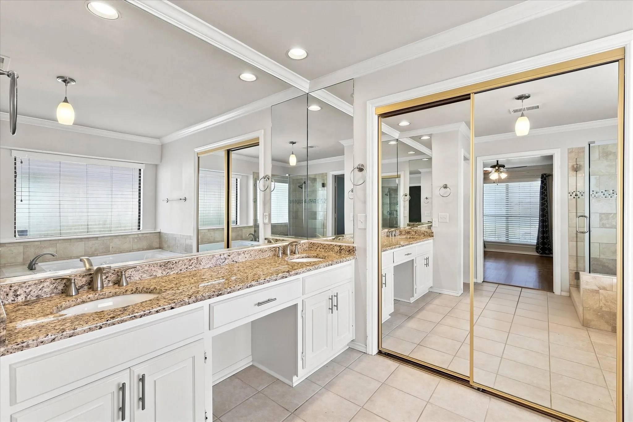 Double vanity with granite-style countertop, white cabinetry, and undermount sinks