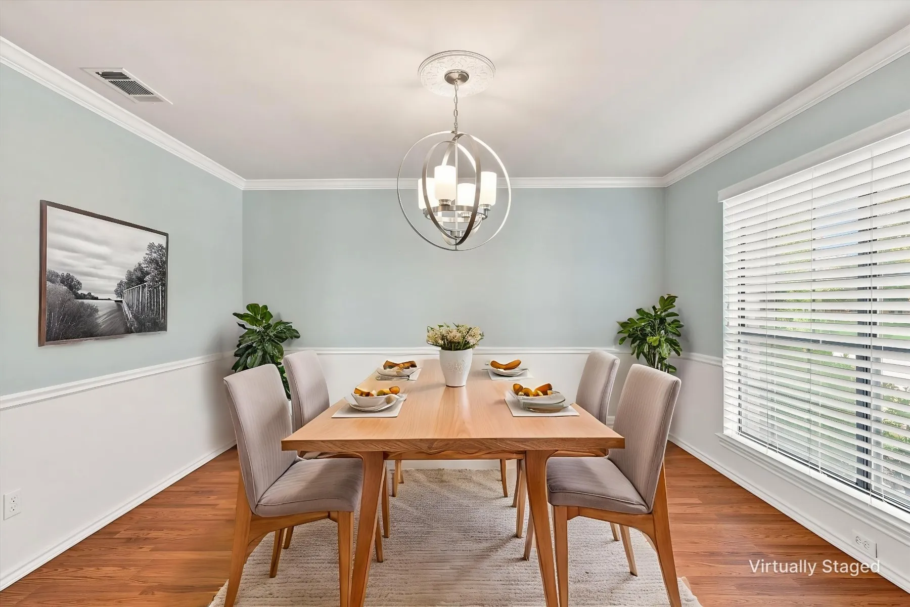 Hardwood-style flooring, crown molding, wainscoting, and a contemporary chandelier