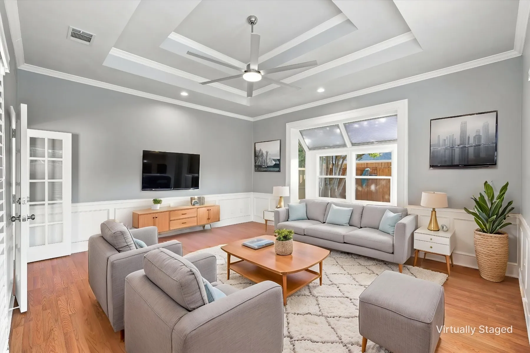 Tray ceiling with recessed lighting and a ceiling fan, wood-finish flooring, wainscoting, and a multi-pane window